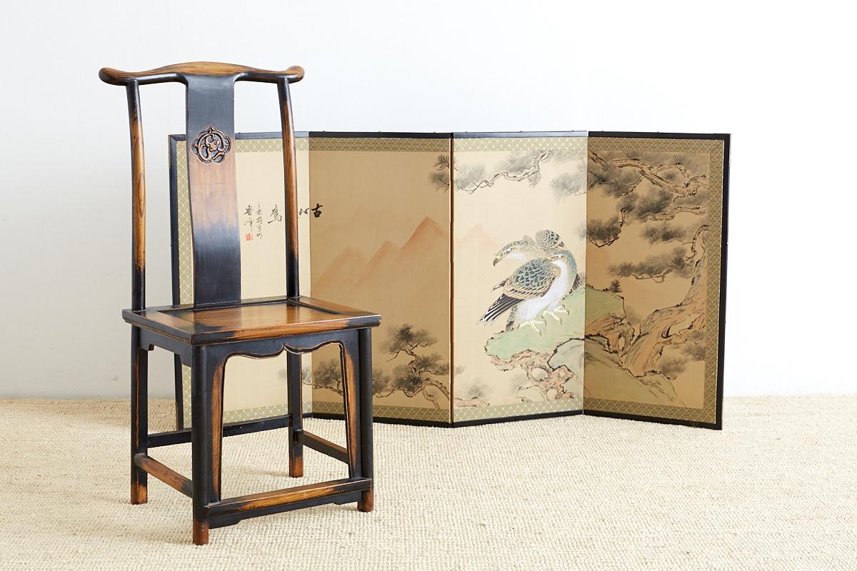 Dramatic Japanese four-panel screen of two hawks in a giant ancient pine tree. Painted in the Kano school style showing perched hawks lurking on prey with a faint mountain background. Intricately painted with strong brush strokes and colors. Signed