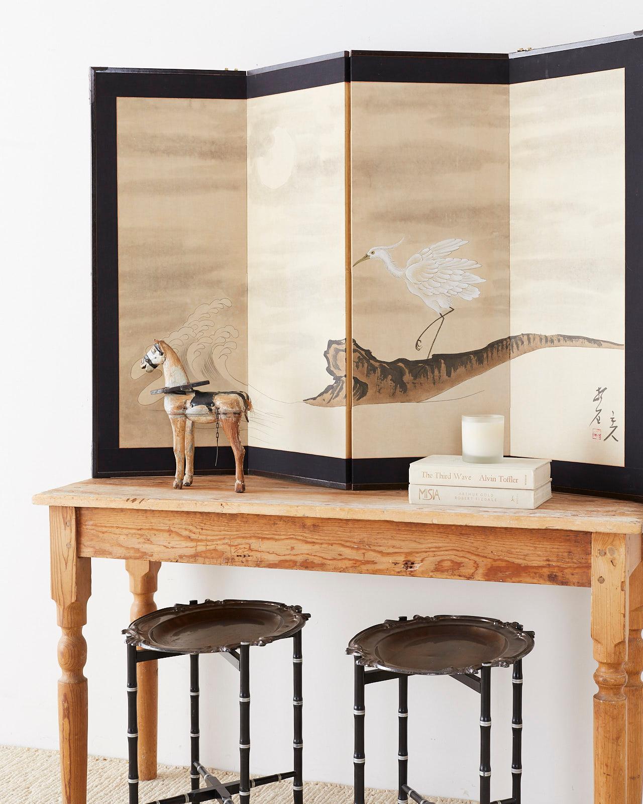 Modern style Japanese four-panel folding byobu screen depicting a white egret with crashing waves under a full moon. Painted with ink and color on textured paper. Signed on right side by artist Shoshi with a seal. Set in a lacquered wood frame with