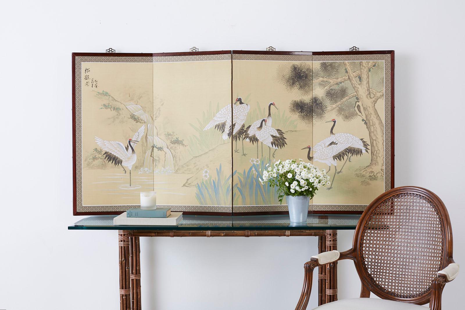 Exquisite Japanese four panel byobu screen depicting red crowned cranes or manchurian cranes. Beautiful landscape scene with a lake and waterfall. The right side has a pine tree and there are foliate and flower blooms in the foreground. Set in a