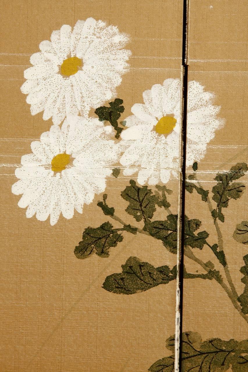 Vintage Byobu, écran de soie à quatre panneaux, représentant de délicats chrysanthèmes et un petit oiseau. Le fond est en soie dorée peinte à la main et bordée d'un brocart de soie. Tache de dégât des eaux sur le côté supérieur droit de ce grand