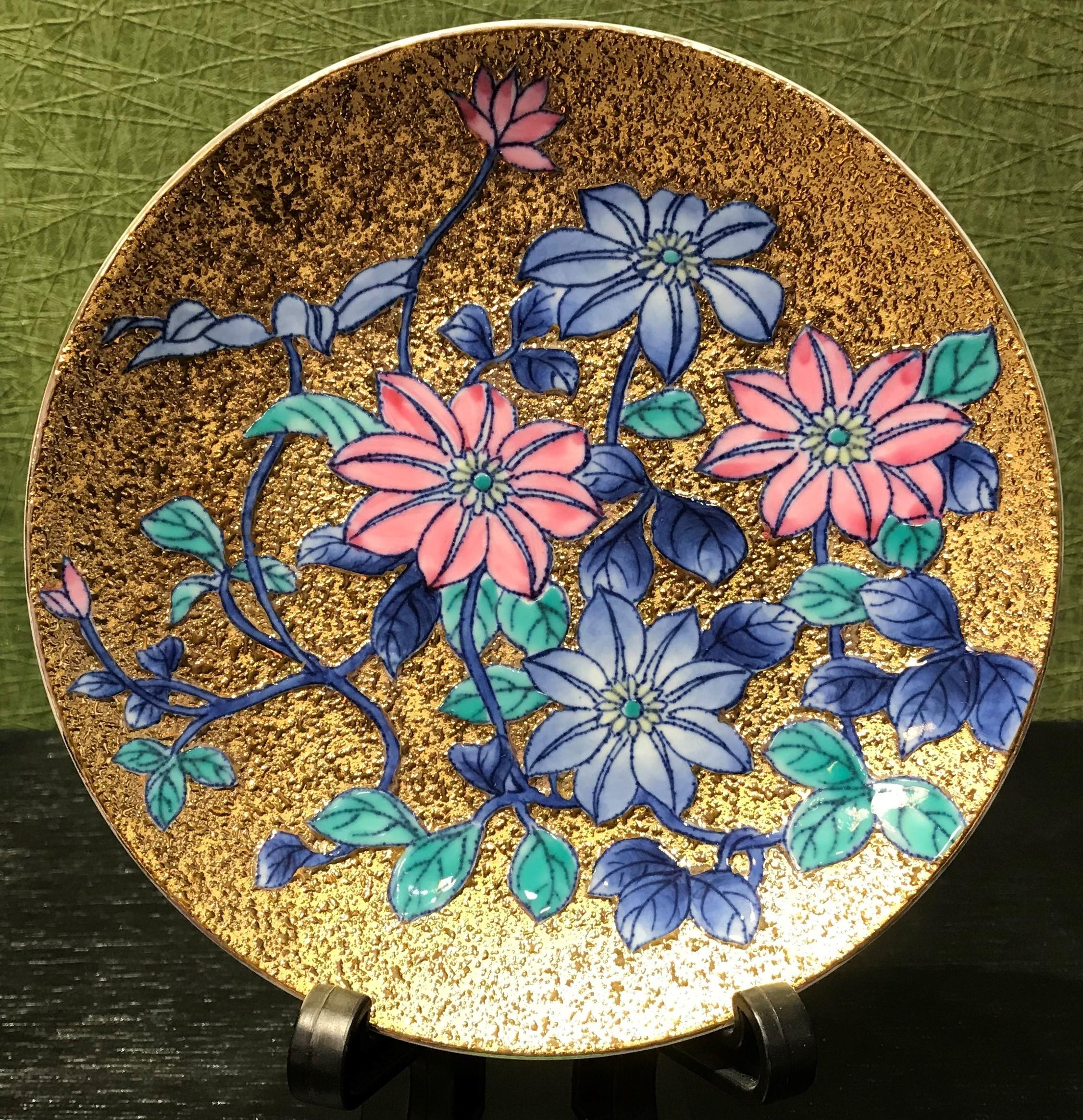 Exquisite contemporary gilded fine porcelain cup and saucer, intricately hand painted in vivid blue and pink on an attractive gilded body, featuring stunning clematis flowers in full bloom.
This cup and saucer is from a signature series by a highly