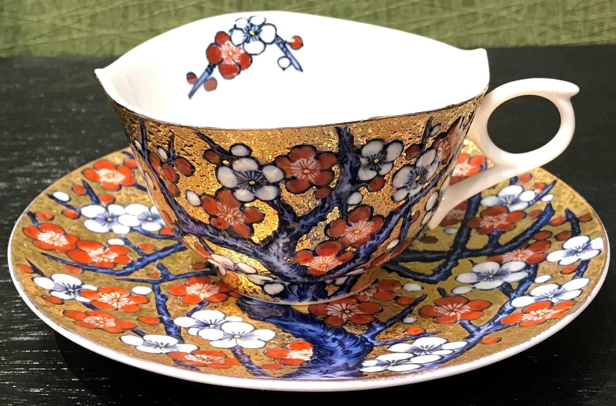 Unique contemporary gilded Japanese fine porcelain cup and saucer, intricately hand painted in vivid blue, red and white on an attractive gilded body, featuring stunning plum blossoms in full bloom.
This cup and saucer is from a signature series by