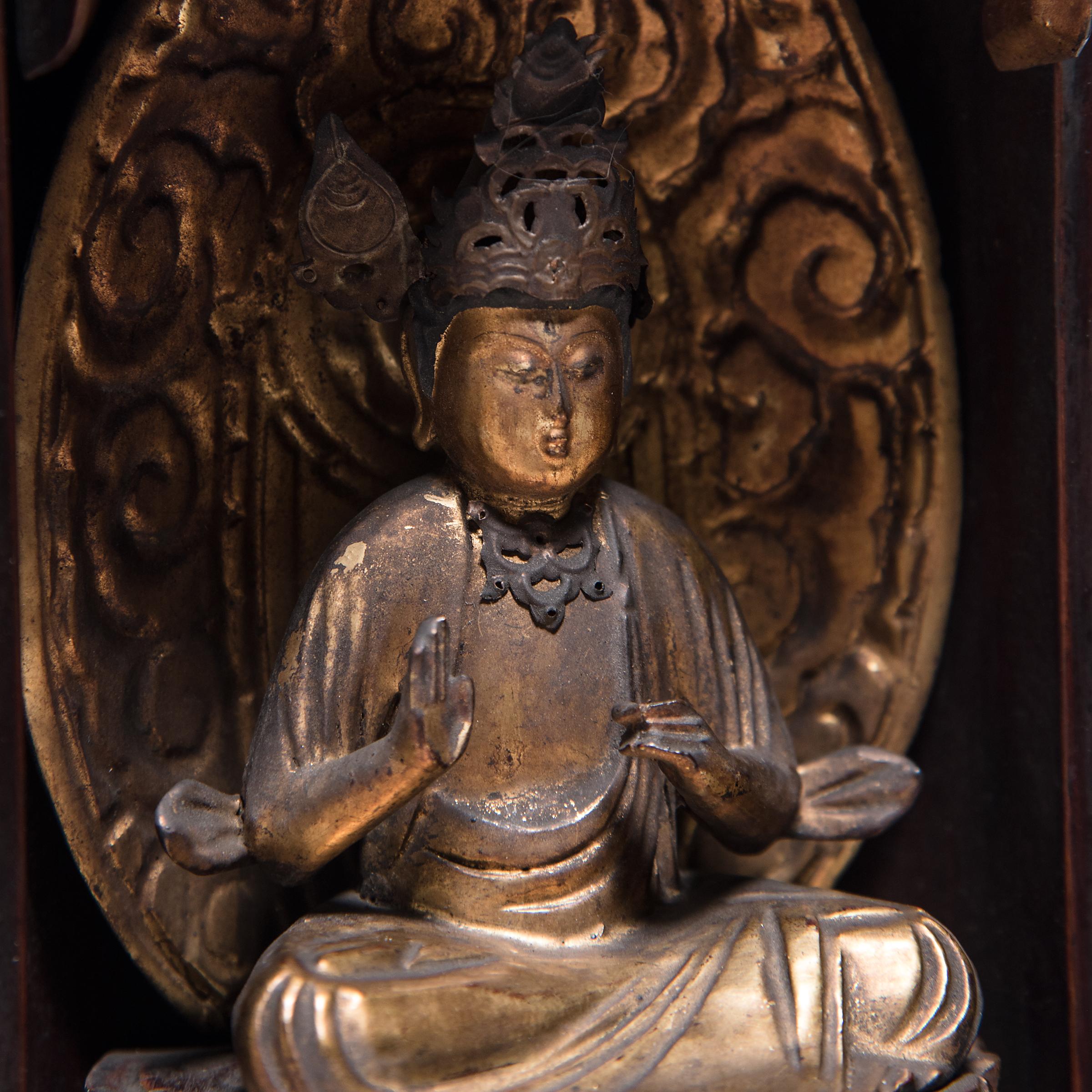 The simple exterior of even black lacquer that encases this 19th century Japanese traveling shrine belies the splendor within. The hinged doors open to reveal an intricately carved gilt figure of the bodhisattva Guanyin, known in Japanese Buddhism