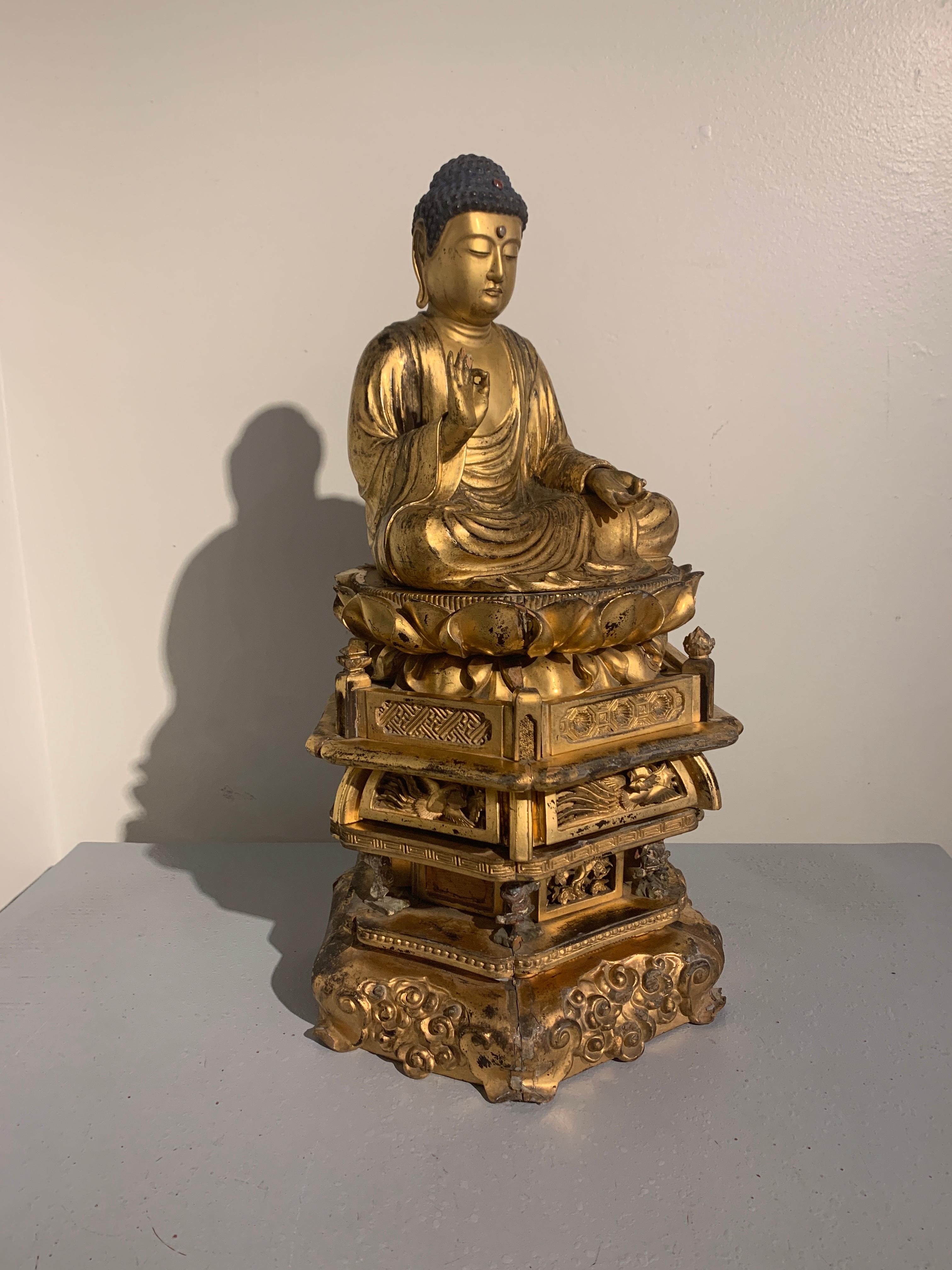 A magnificent Japanese carved and giltwood figure of the Medicine Buddha, Yakushi Nyorai, seated upon a double lotus pedestal supported by a multi-tiered stand, mid-Edo Period, late 18th century.

Yakushi Nyorai, as the Medicine Buddha is known in