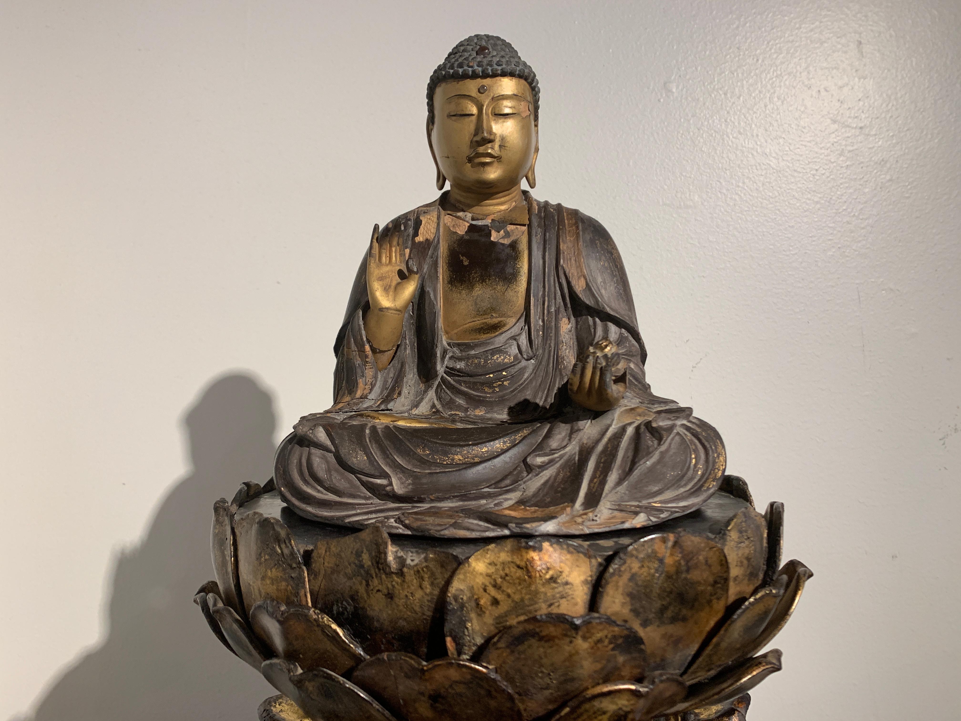 Remarquable figure japonaise en bois laqué et doré de la fin de la période Muromachi (1333-1573) représentant Yakushi Nyorai, le Bouddha de la Médecine, assis sur un piédestal en lotus ajouré et sculpté, Japon, milieu du XVIe siècle.

Le Bouddha de