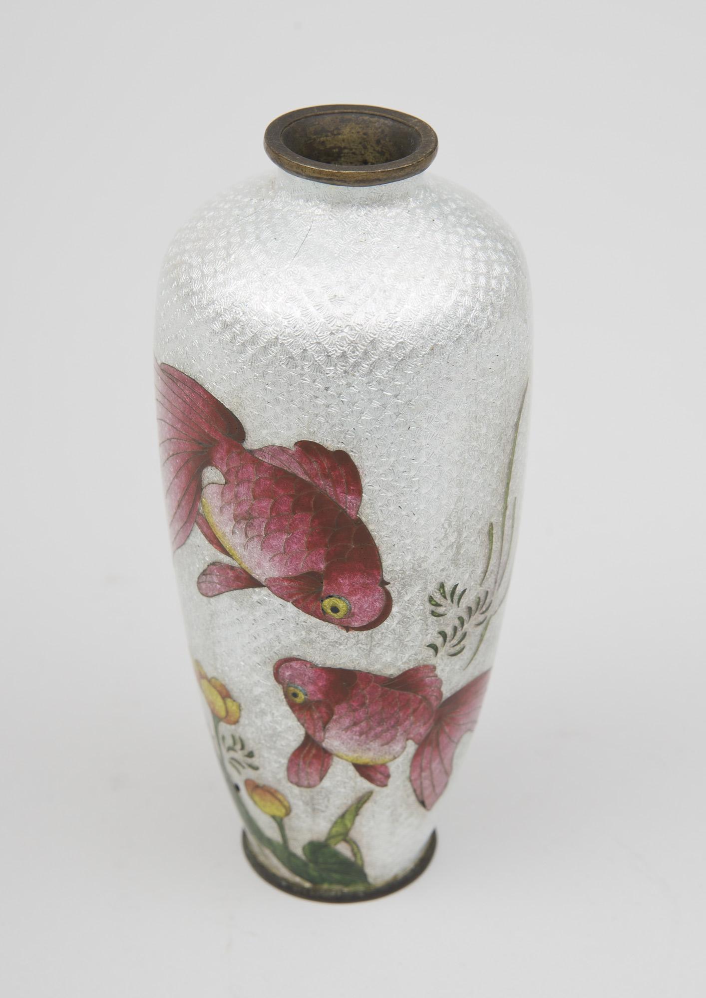 Ginbari cloisonne miniature vase decorated with two reddish-pink koi swimming amongst yellow-gold flowers on a translucent white background. Meiji Period (1868-1912).
Ginbari is a Japanese term that is a type of cloisonne with clear enamel over a