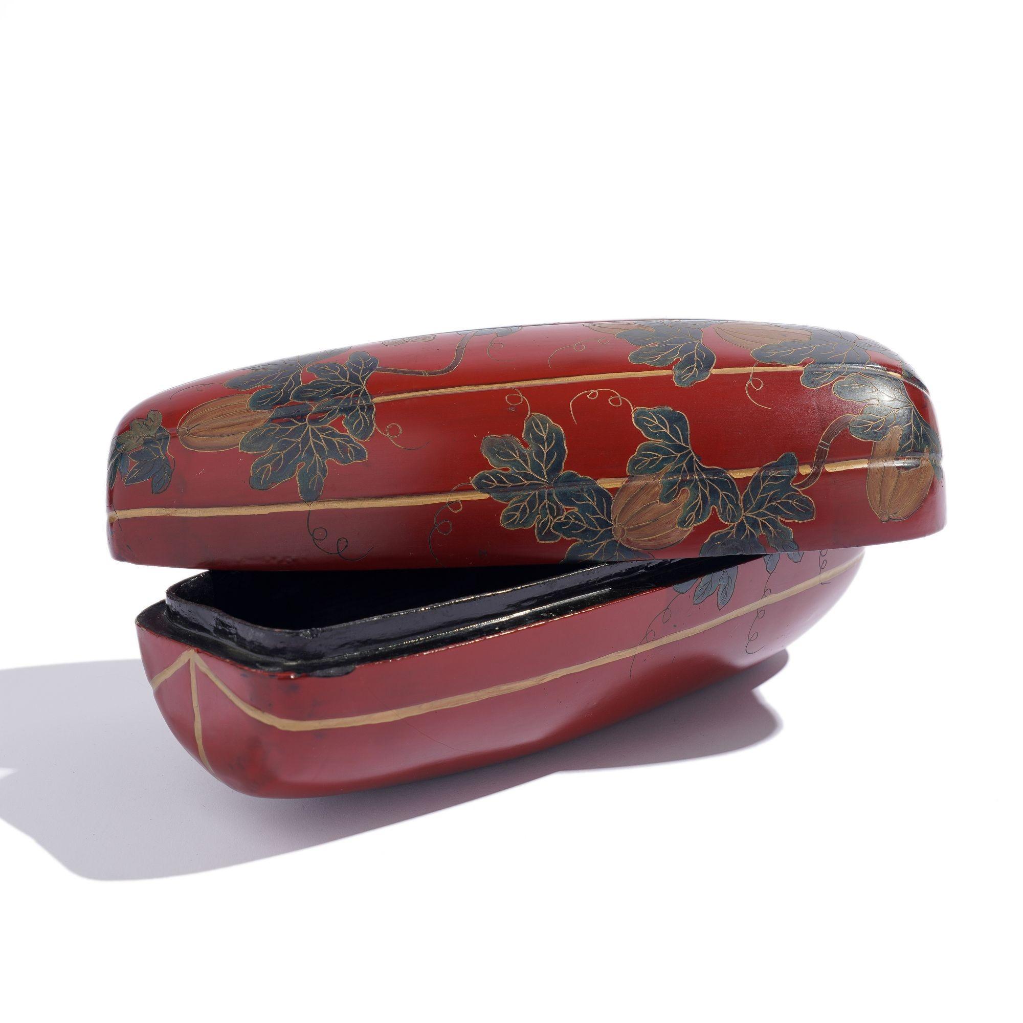 A hand carved wood & cinnabar red lacquered gourd shaped covered box. The exterior of the box is incised with gilt outlined dark green leafy vines, gilt gourds, flowers, and butterflies on a grooved pattern simulating the gourd shape. The interior