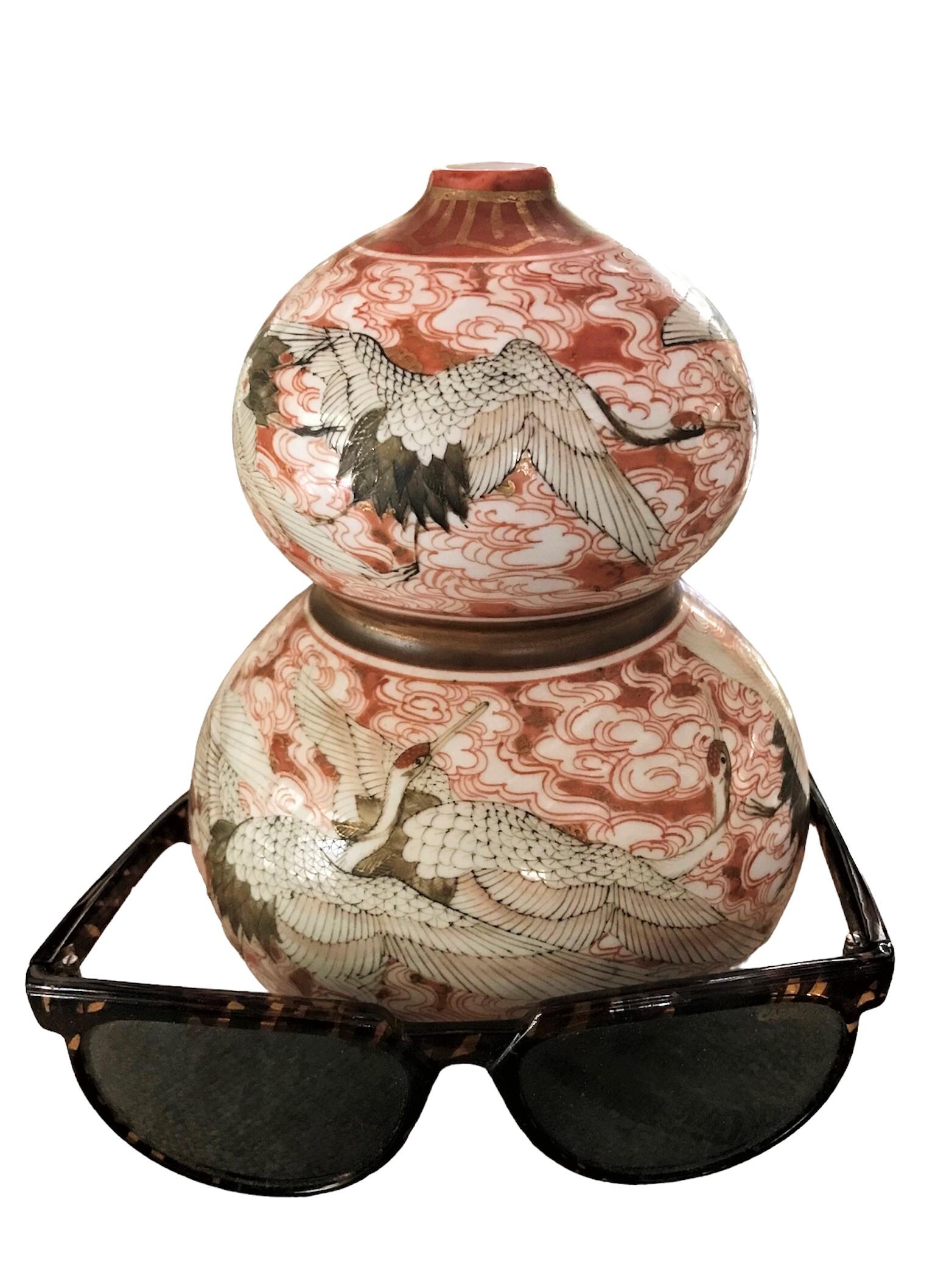 Exotic gourd shape Kutani ceramic vase with flying Cranes decoration from Mid Century Japan.  The hand painting was done with great care and artistic knowledge.  The vase is painted with swirling clouds decoration with 4 single cranes in the upper