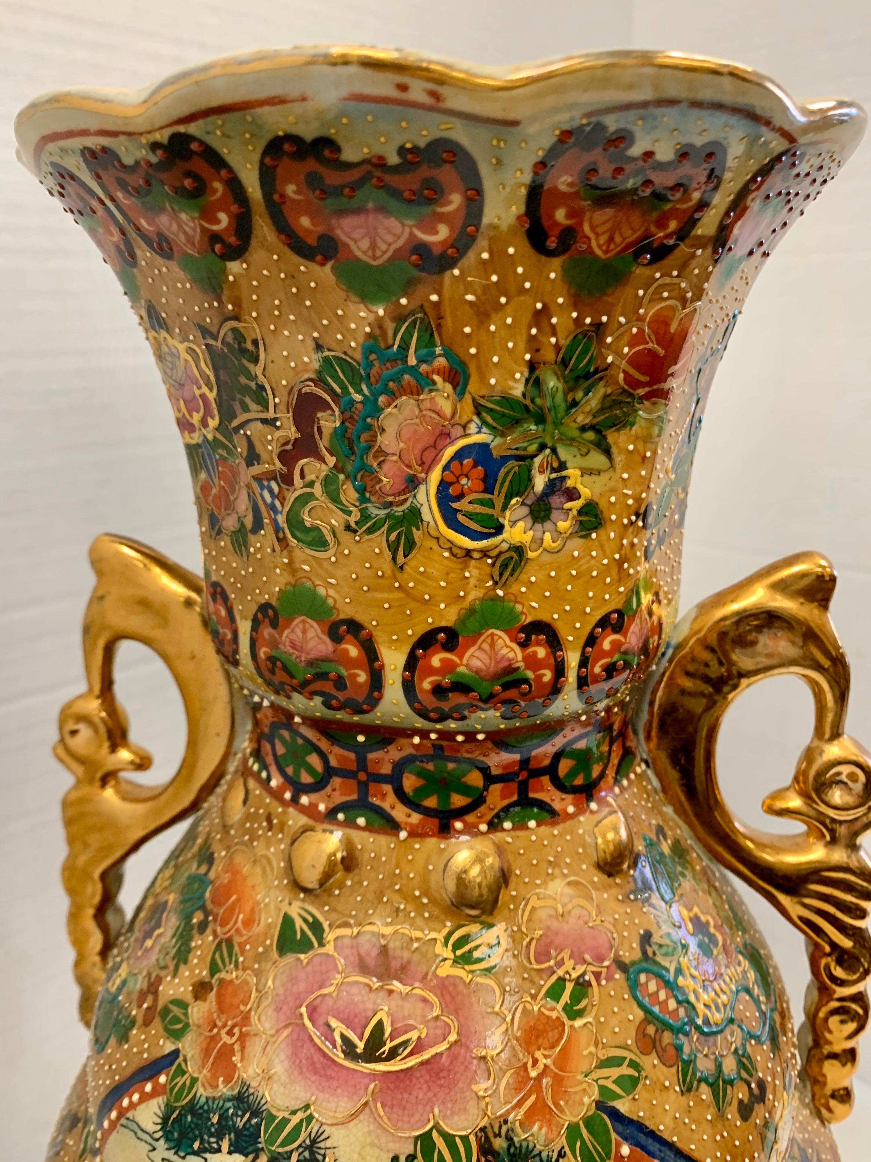 Stunning Japanese porcelain vase wit intricately hand painted scenery of Japanese women. Gorgeous floral detail with raised gold outline adorns the balance of the vase. Handles are a gilt color as well and lastly there are four foo dog heads at