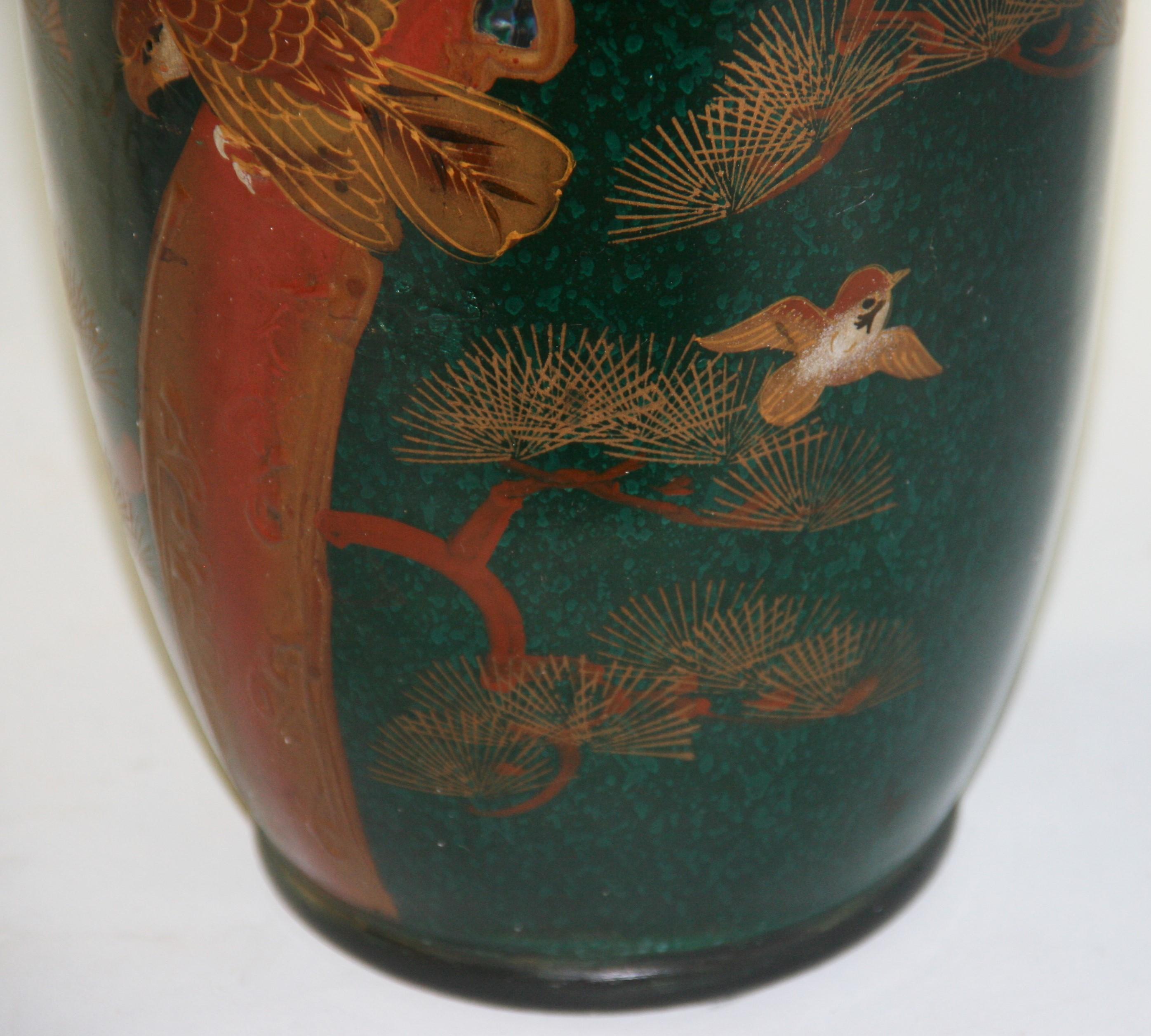 1652 Vase japonais peint à la main avec un aigle en relief sur une branche d'arbre.
Fond vert foncé et vert clair  Avec une pierre verte incrustée sur la branche.
Fabriqué par Ucagco ceramics 1946-1956 avec autocollant de la société sur le fond 