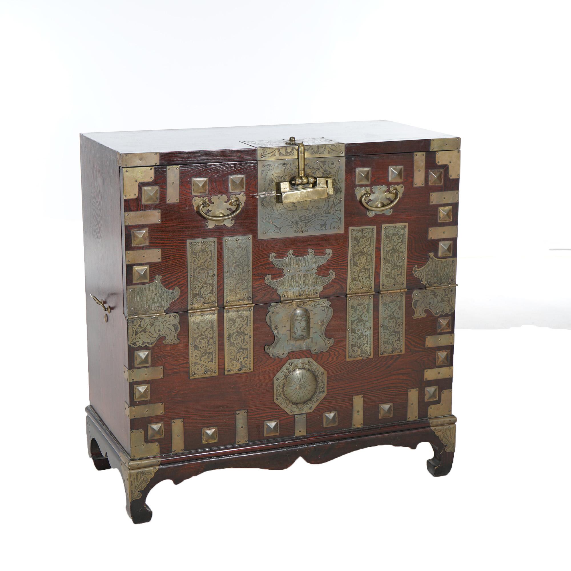 A Japanese Tonsu bar cabinet offers hardwood construction with drop down door opening to storage compartment with upper drawers; exterior with shaped brass foliate engraved plates throughout, 20th century

Measures- 35.5''H x 34''W x 17.5''D