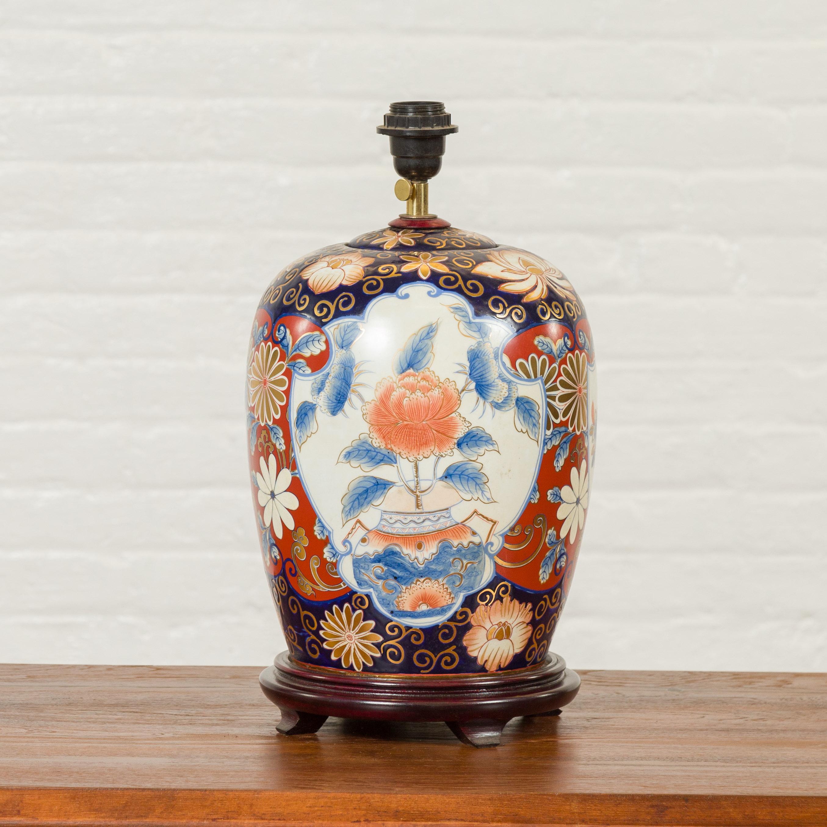 A Japanese Imari ceramic table lamp from the 20th century mounted on a custom base. Created in Japan during the 20th century, this table lamp features a midnight blue, red and golden decor accented with white cartouches highlighting the presence of