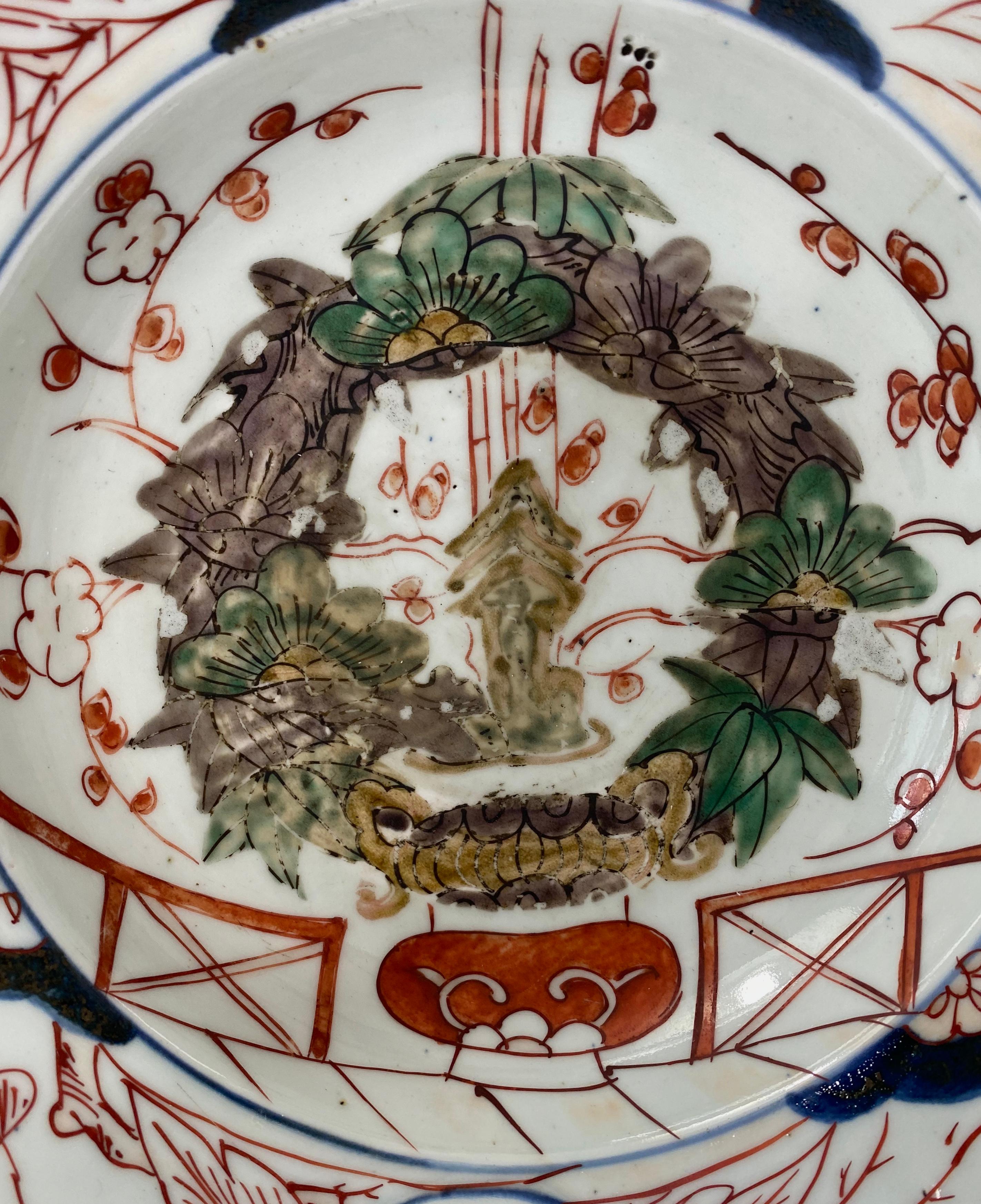 Japanese ‘Imari’ porcelain barbers bowl, Arita, late 17th century. Edo Period. Hand painted in Imari style, with a jardiniere of flowering plants, unusually enamelled in Kutani taste, upon a terrace. The broad, flared rim, painted with further
