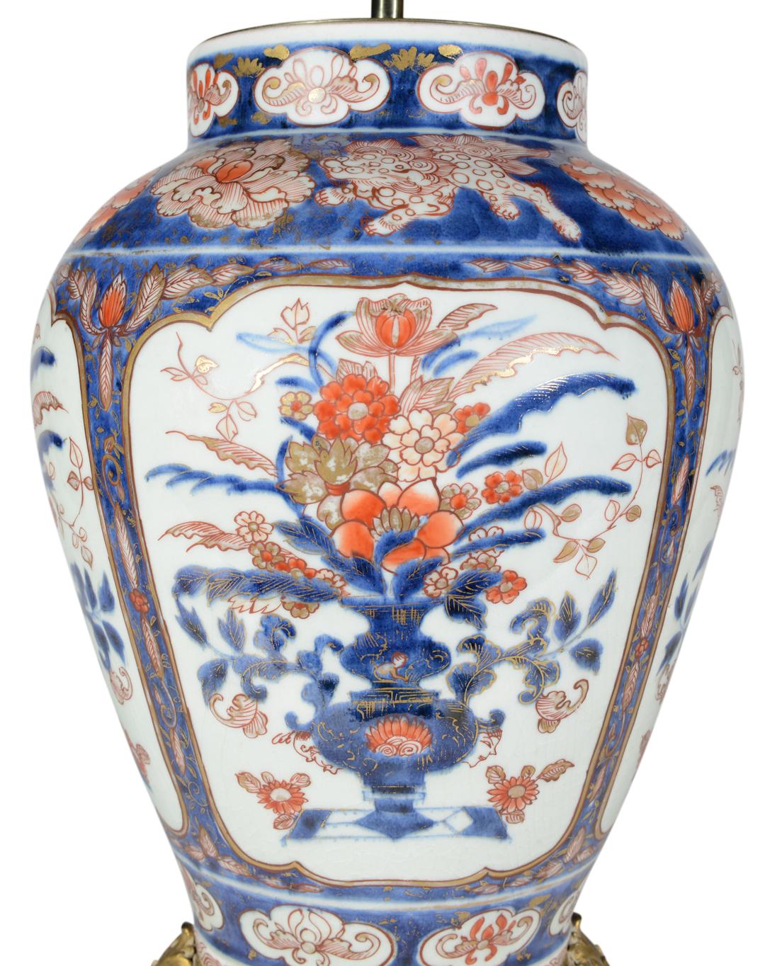 Superbe paire de vases japonais Imari du début du XVIIIe siècle, décorés dans la palette typique de tons bleus, rouges de fer et de reflets dorés sur un fond à prédominance blanche. Les corps sont finement peints de panneaux incorporant des vases