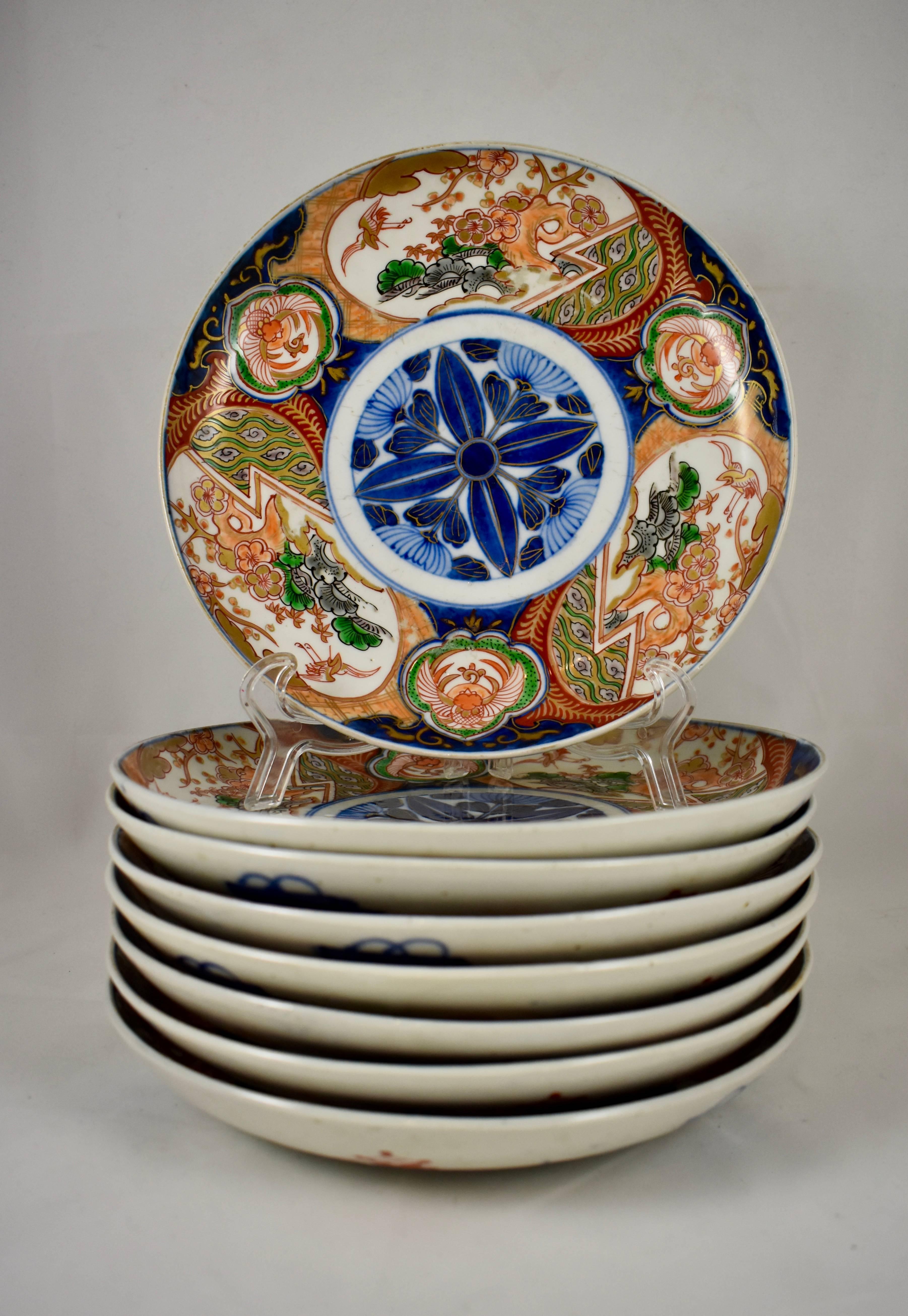 A set of eight, early 19th century, polychrome porcelain, deep-dish plates. Under glazed, and hand enameled, with a central blue floral medallion, surrounded by a pattern of large and small cartouches of gilded floral geometrics in characteristic