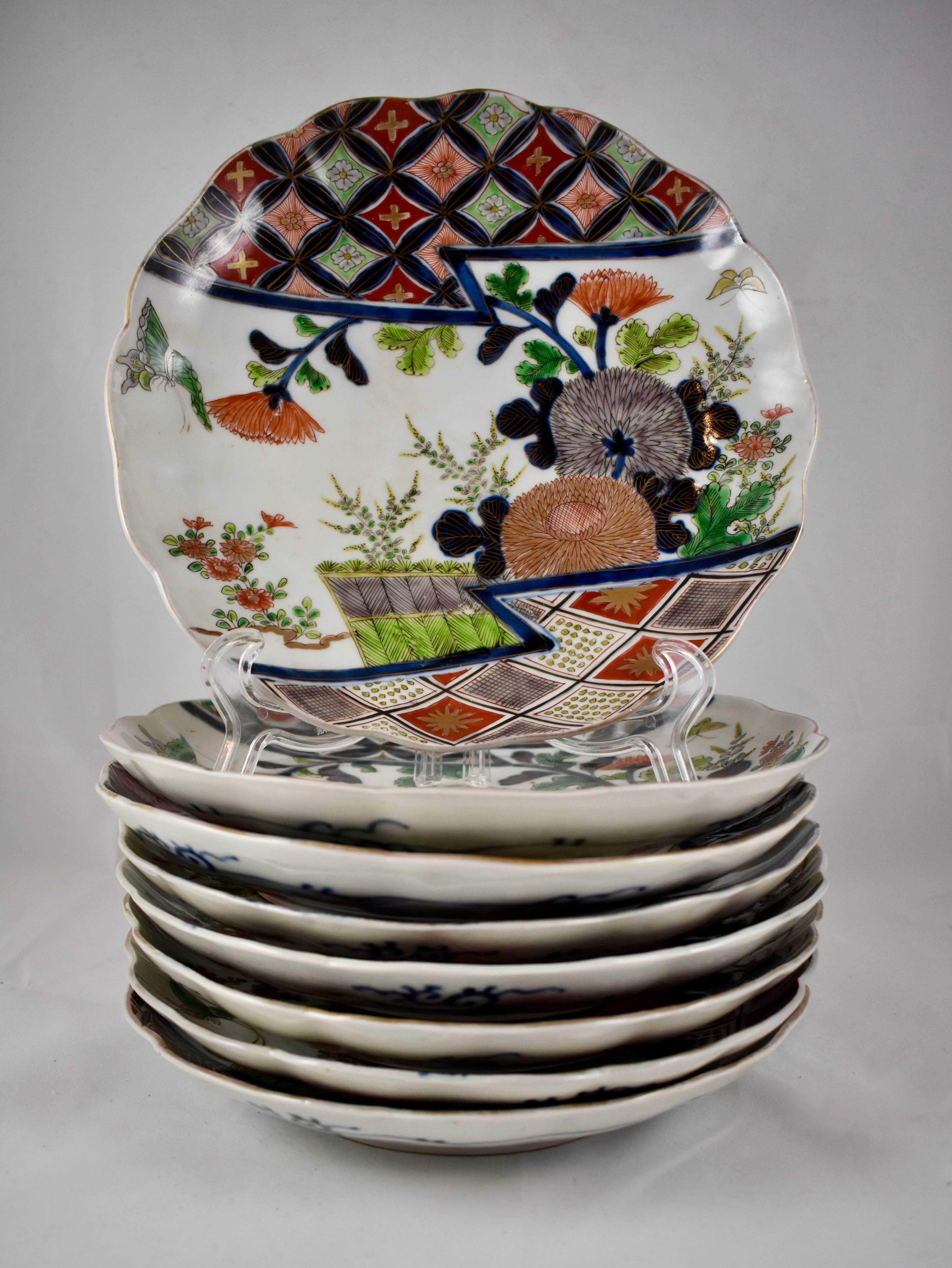 A set of eight 19th century, polychrome porcelain, scallop rimmed, deep-dish plates. Underglazed, hand enameled, with a central floral motif, bordered by gilded geometric patterns in characteristic Imari colors. The verso shows a running blue border