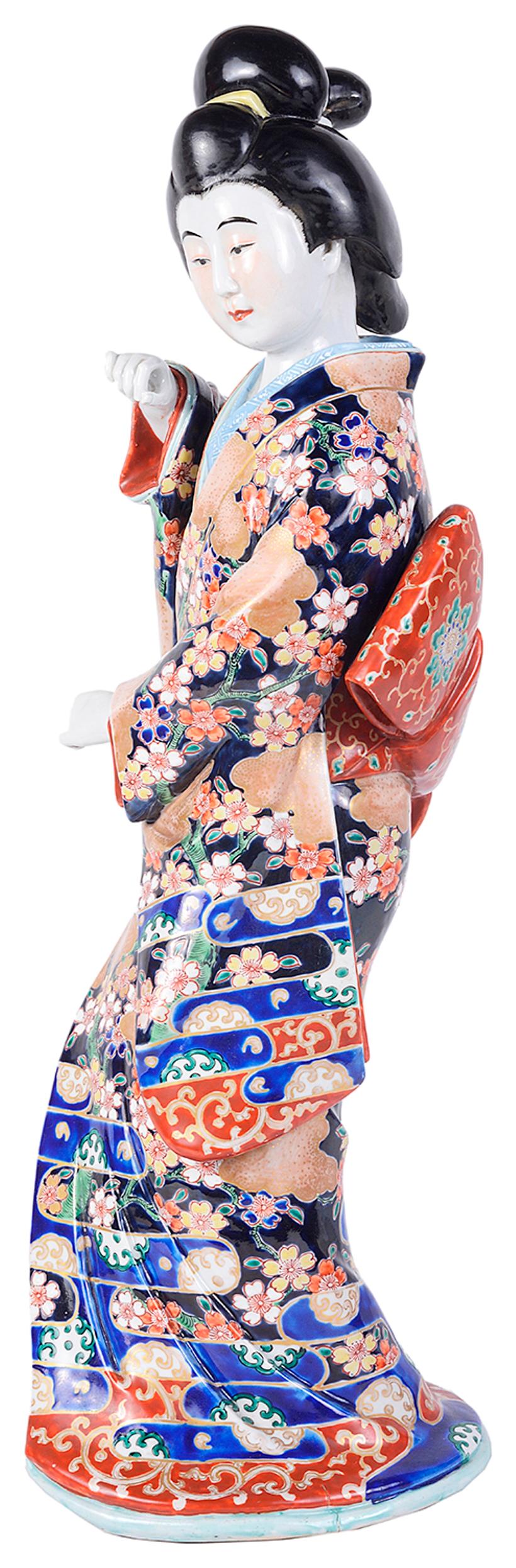 A large early 20th century Japanese Imari porcelain figure of a Geisha girl wearing an exotic colored kimono.