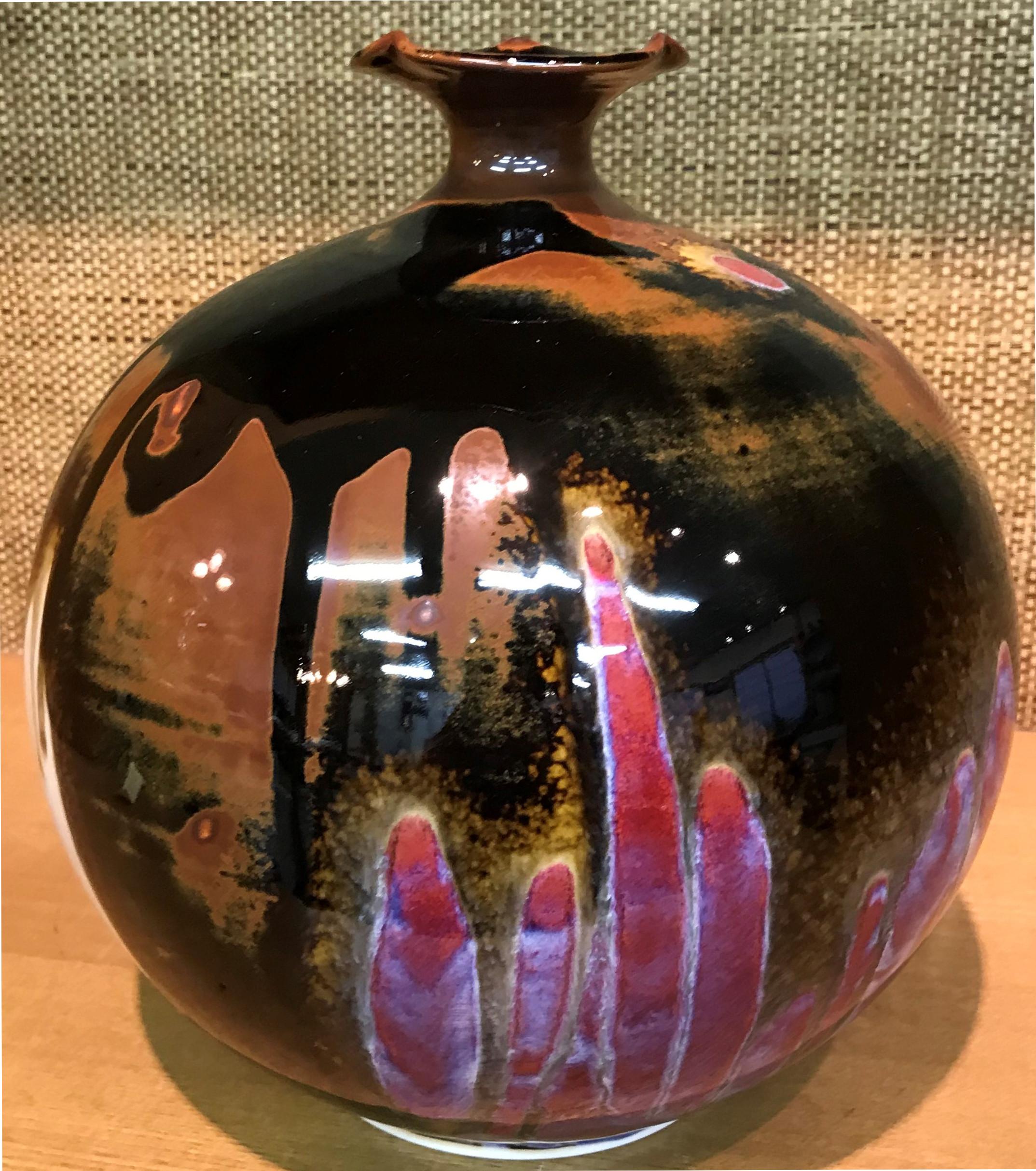 This unique Japanese contemporary hand-glazed decorative porcelain vase features the artist’s signature red, blue and brown colors set against a black background. The creator of this piece is a third generation porcelain artist of the Imari-Arita