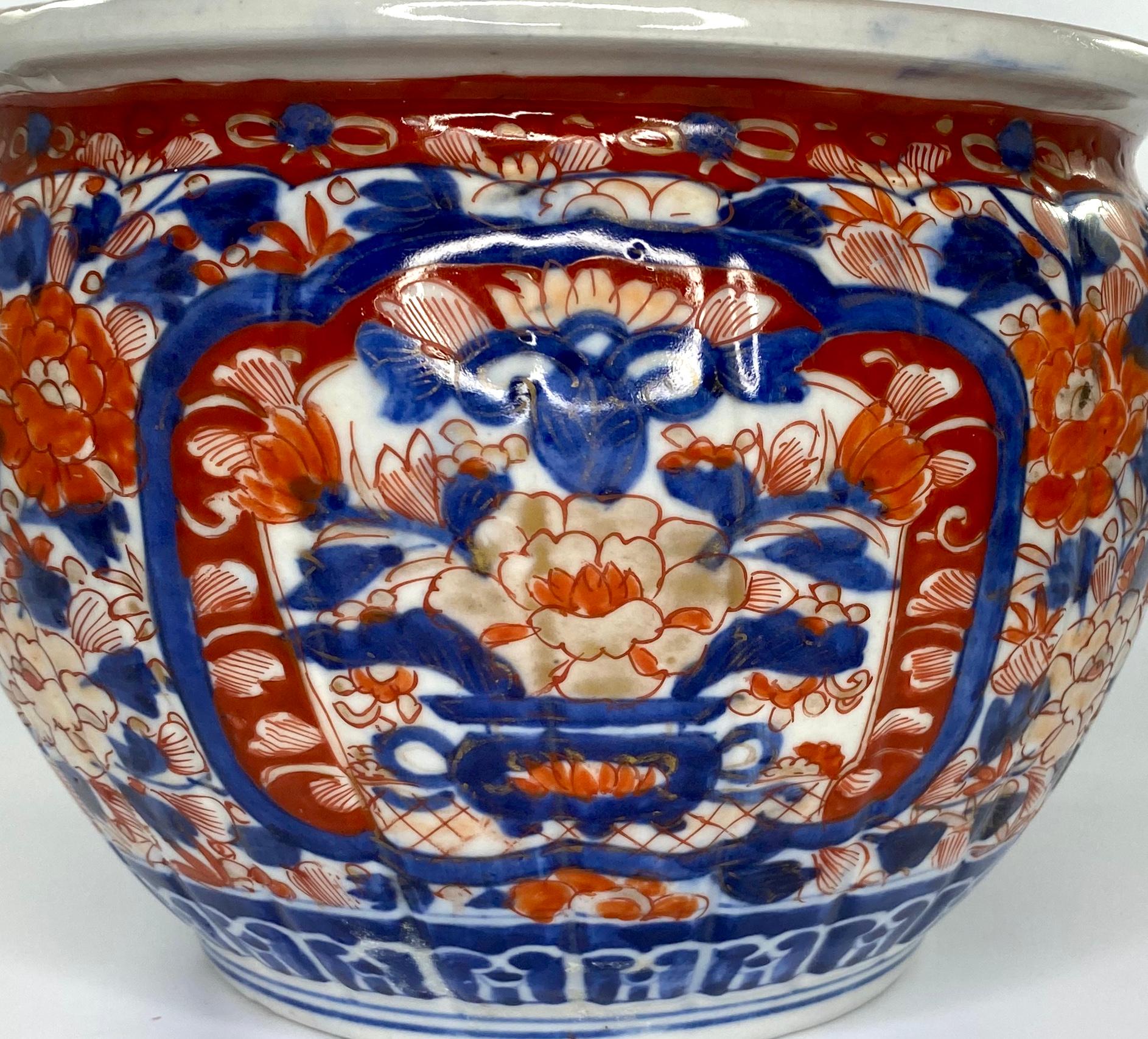 Japanese ‘Imari’ porcelain jardinière, circa 1890, Meiji Period. The lightly fluted jardiniere hand painted in typical Imari colors, with shaped panels containing vases of flowers, and flowering plants, on a ground of dense, stylised flowering