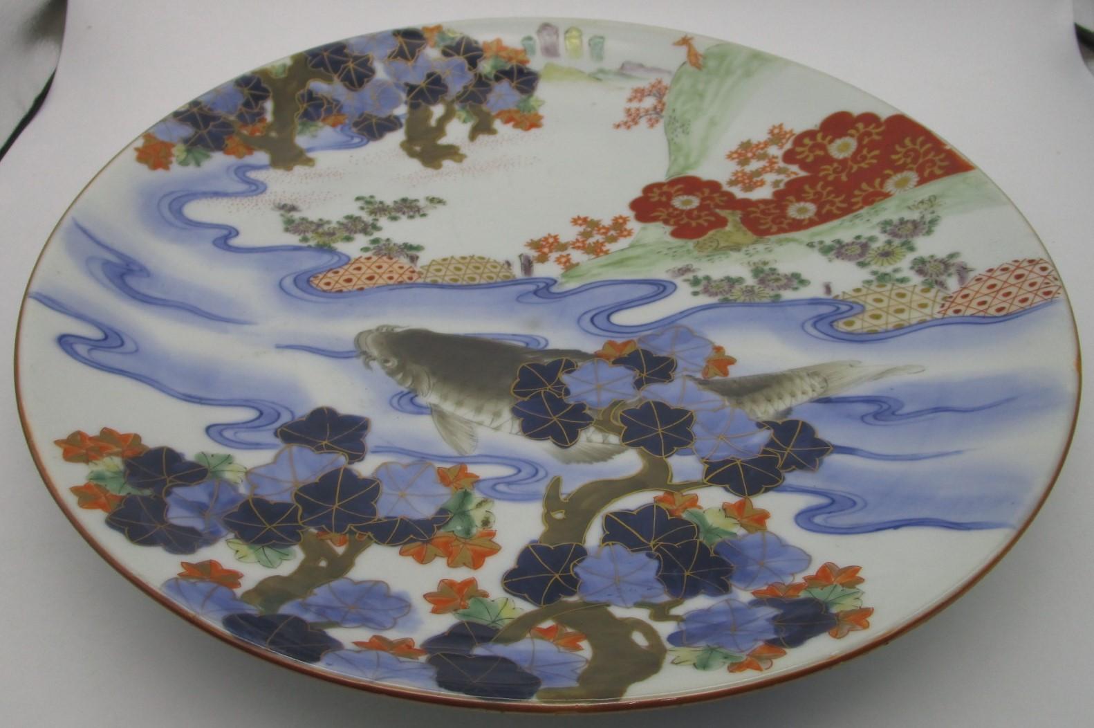 Unique Japanese large Imari Meiji period porcelain charger in iron-red, cobalt blue and green. It showcases a dramatic scene with a bold koi fish in deep green swimming in a river in underglaze cobalt blue, decorating the center part of the charger