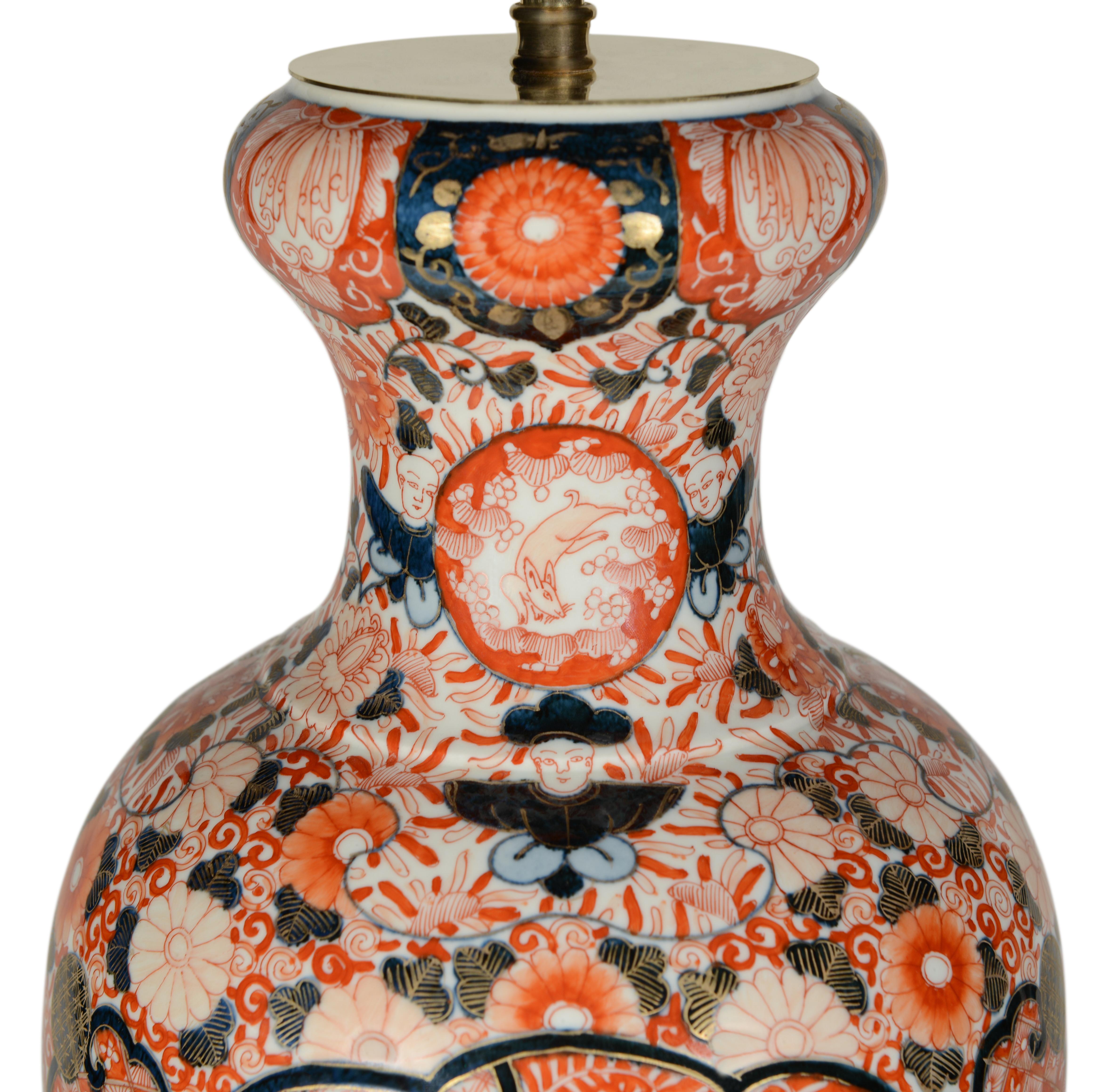 Magnífico par de jarrones balaustres japoneses de finales del siglo XIX, densamente decorados en toda su superficie con la típica paleta Imari de rojos y azules férreos sobre fondo blanco, ahora montados como lámparas con bases torneadas doradas a