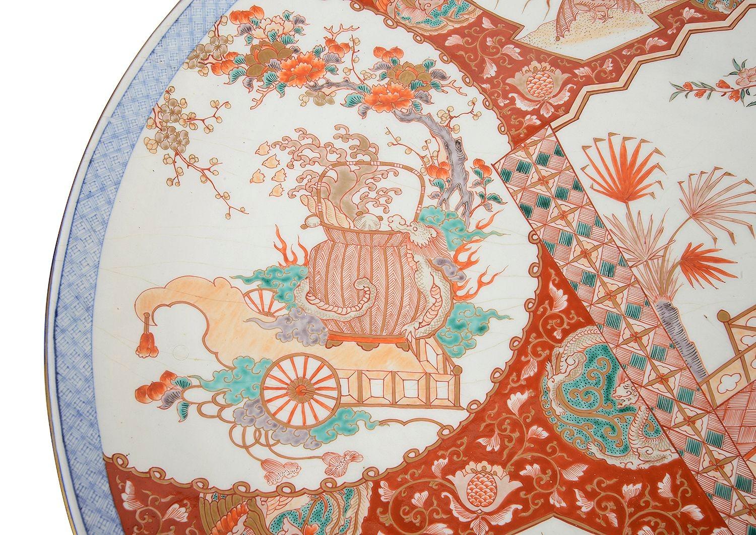 A good quality late 19th Century Japanese porcelain Imari circular wall charger. Having wonderful hand painted scenes of fan shaped panels depicting a boy carrying logs for his master, and a cart carrying a basket. Classical motif and scrolling