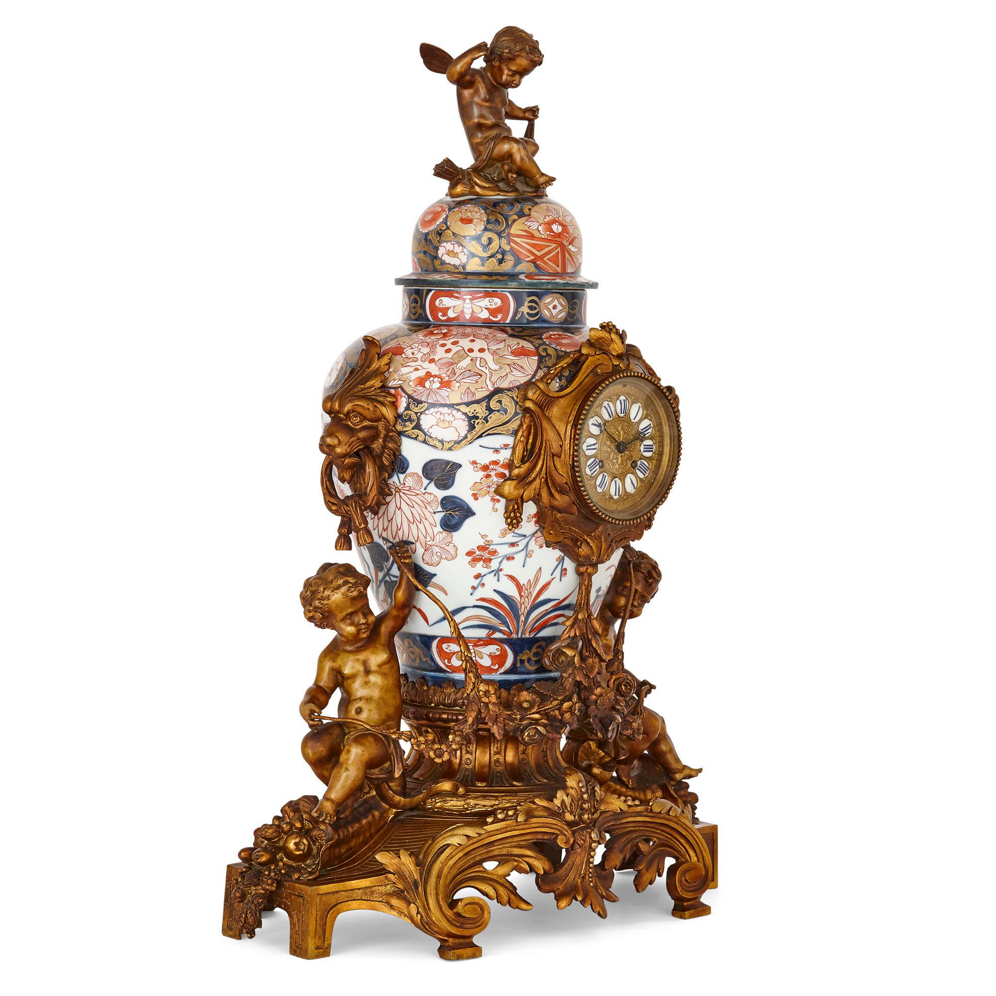 This clock set contains three pieces: namely, a mantel clock and a pair of flanking candelabra. The mantel clock is designed about a Japanese porcelain vase, known as Imari ware. This white ground vase, painted in reds and blues and ornamented with