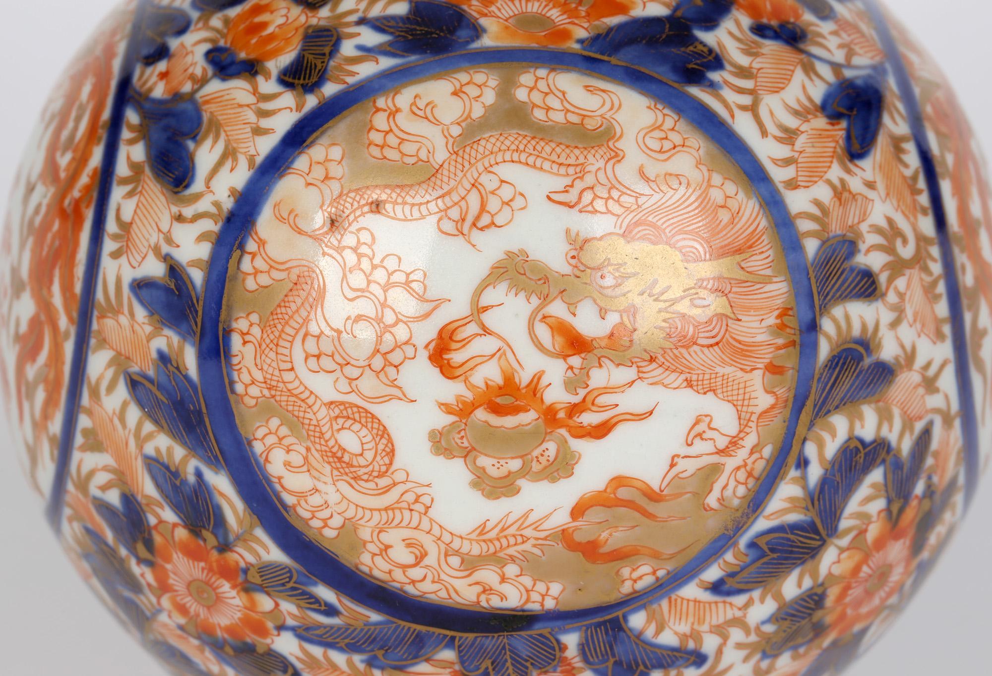 Exceptional Japanese porcelain Imari painted vase with panels containing dragons chasing the flaming pearl and with Ho Ho birds amidst flowering shrubs believed to date to the early 19th century. The vase stands on a narrow rounded foot with a