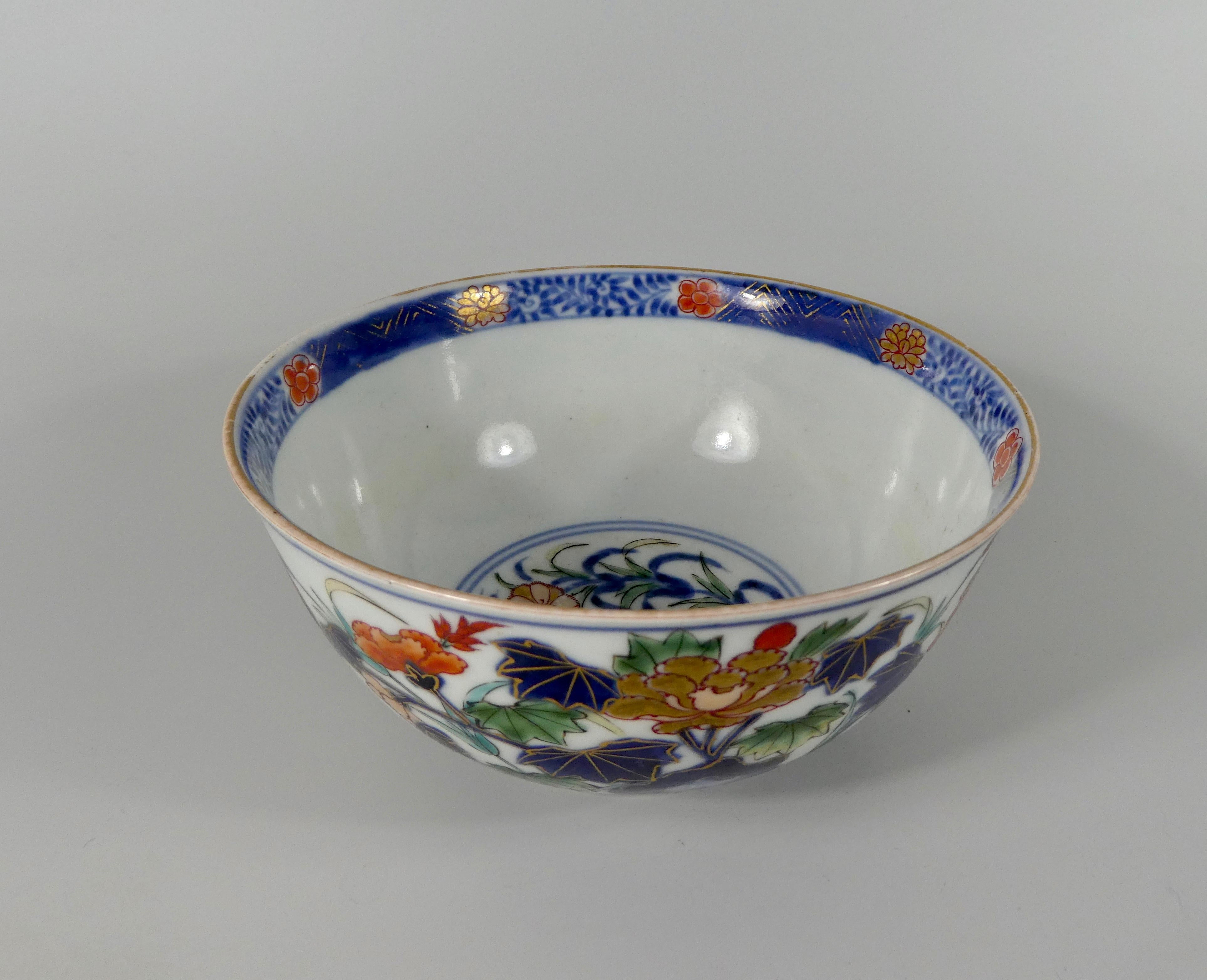 A fine Japanese porcelain bowl, Arita, late 17th-early 18th century. Beautifully painted in ‘Imari’ style, with a continuous scene of flowering plants growing amongst rocks, in underglaze blue, green, yellow, iron red, and heightened in gilt; above