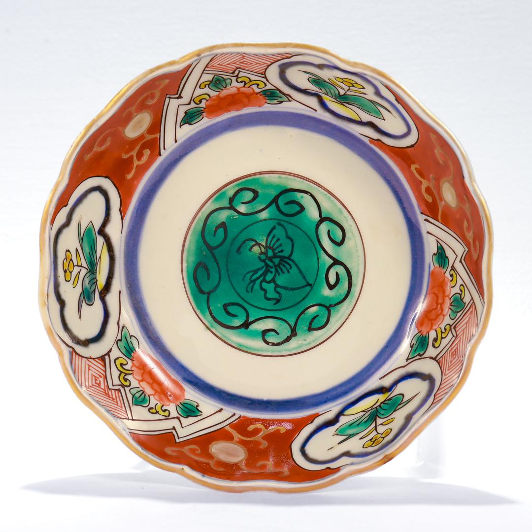 A fine old or antique Japanese Imari porcelain bowl.

With a green butterfly crest to the center surrounded by red, blue, green and yellow geometric & floral devices on a white ground.

The rim is gilt and the exterior of the bowl has blue