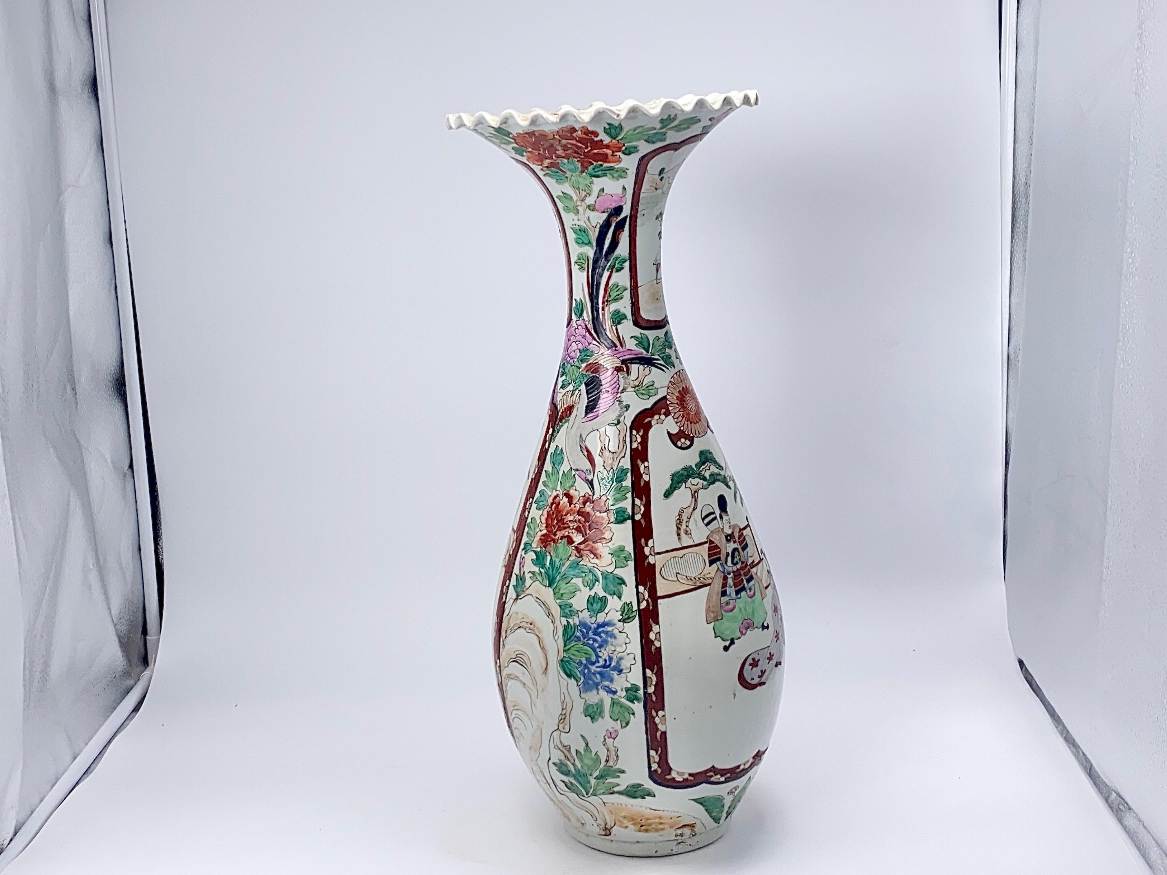 Japanese Imari floor vase offer porcelain construction with each vessel having ruffled rim, hand painted allover floral enamel decoration and garden reserves with birds, and characters, a Samourai and a Woman, c1930. It has been made in Japan circa