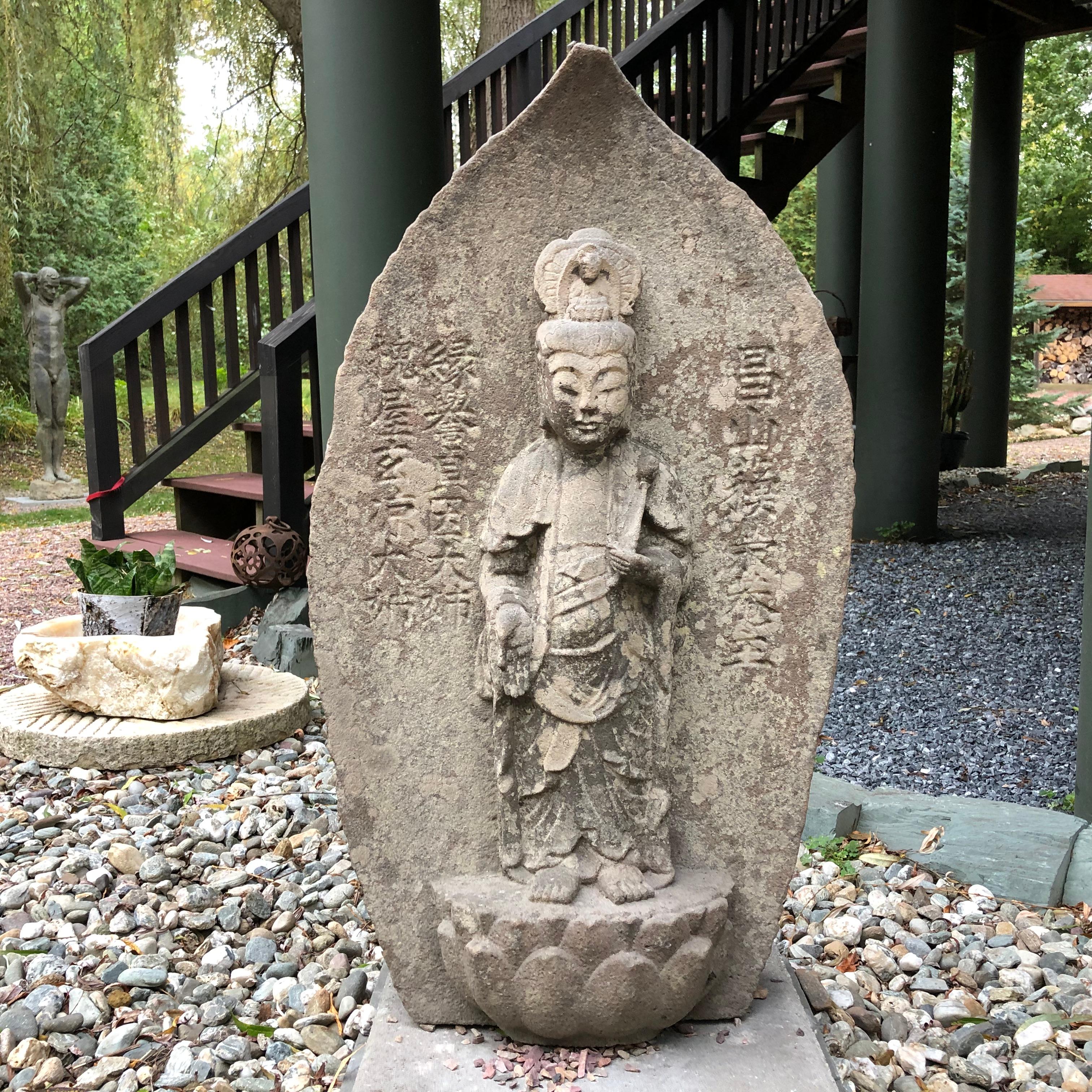 From our recent Japanese Acquisitions Travels

An early, large and hard to find Japanese hand carved stone Kanon Guan Yin carved in dan over all organic leaf form and in a mudra of compassion while clutching a holy flower stem. She has been