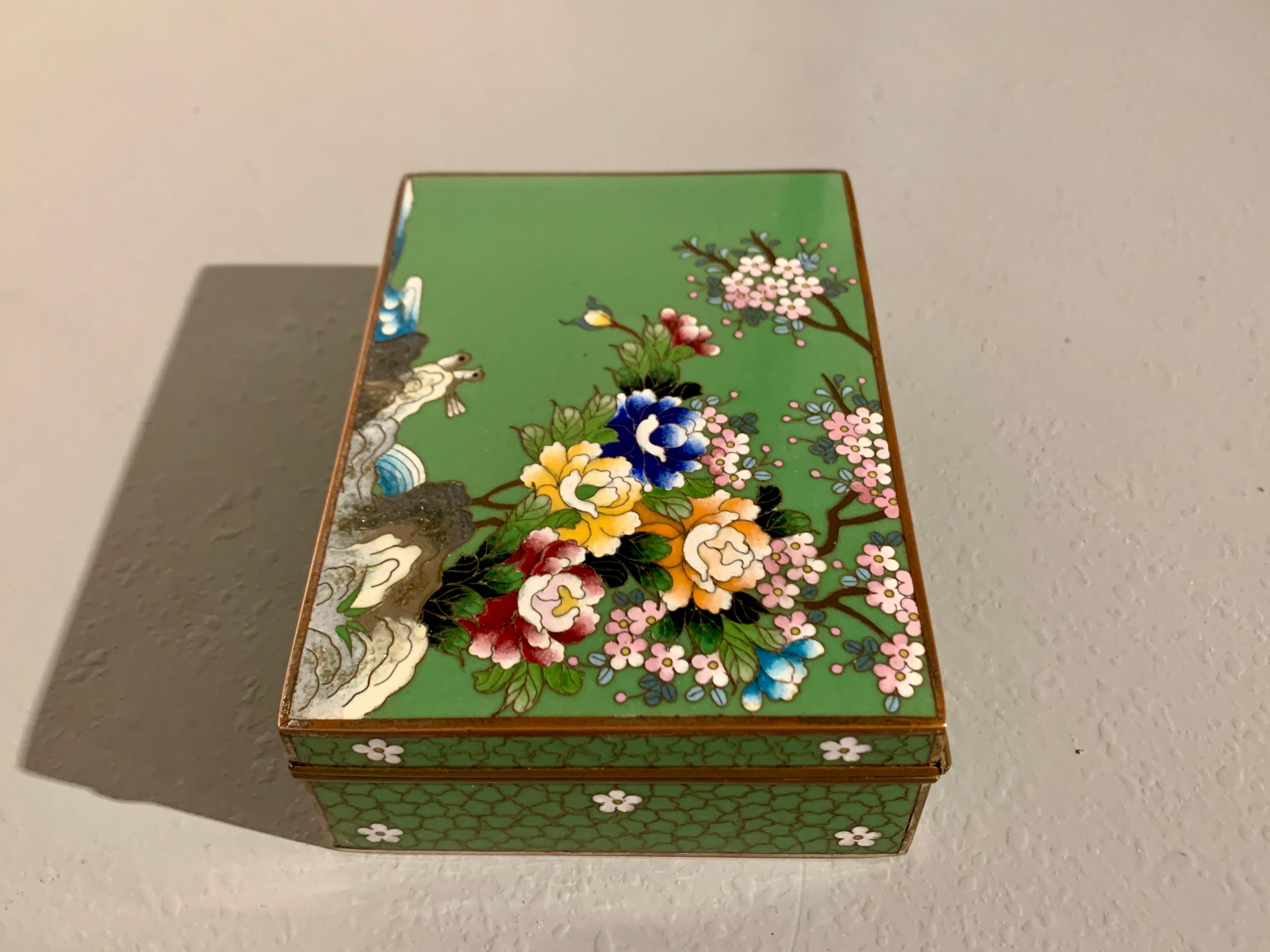 A charming Japanese avocado green cloisonne box by the Inaba Cloisonne Company, late Meiji Period, Japan.

The rectangular box features a hinged top decorated with a birds and flowers against an avocado green enamel ground. 

A large spray of