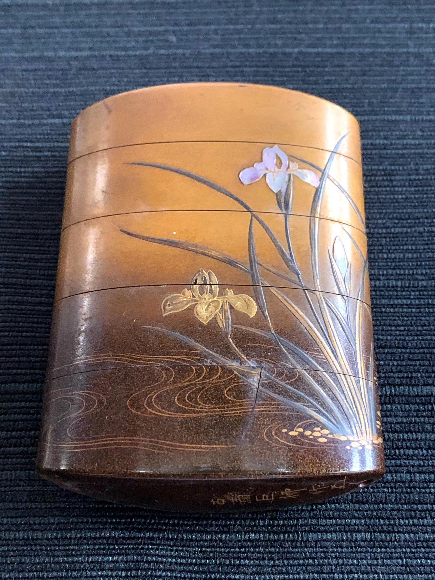 A four-case lacquered inro by Koma Koryu circa 19th century late Edo period. The inro features a pair of Chinese mandarin duck resting under a bundle of blooming irises on the pond. Hiramaki-e and takamaki-e and raden (mother-of-pearl) shell inlay