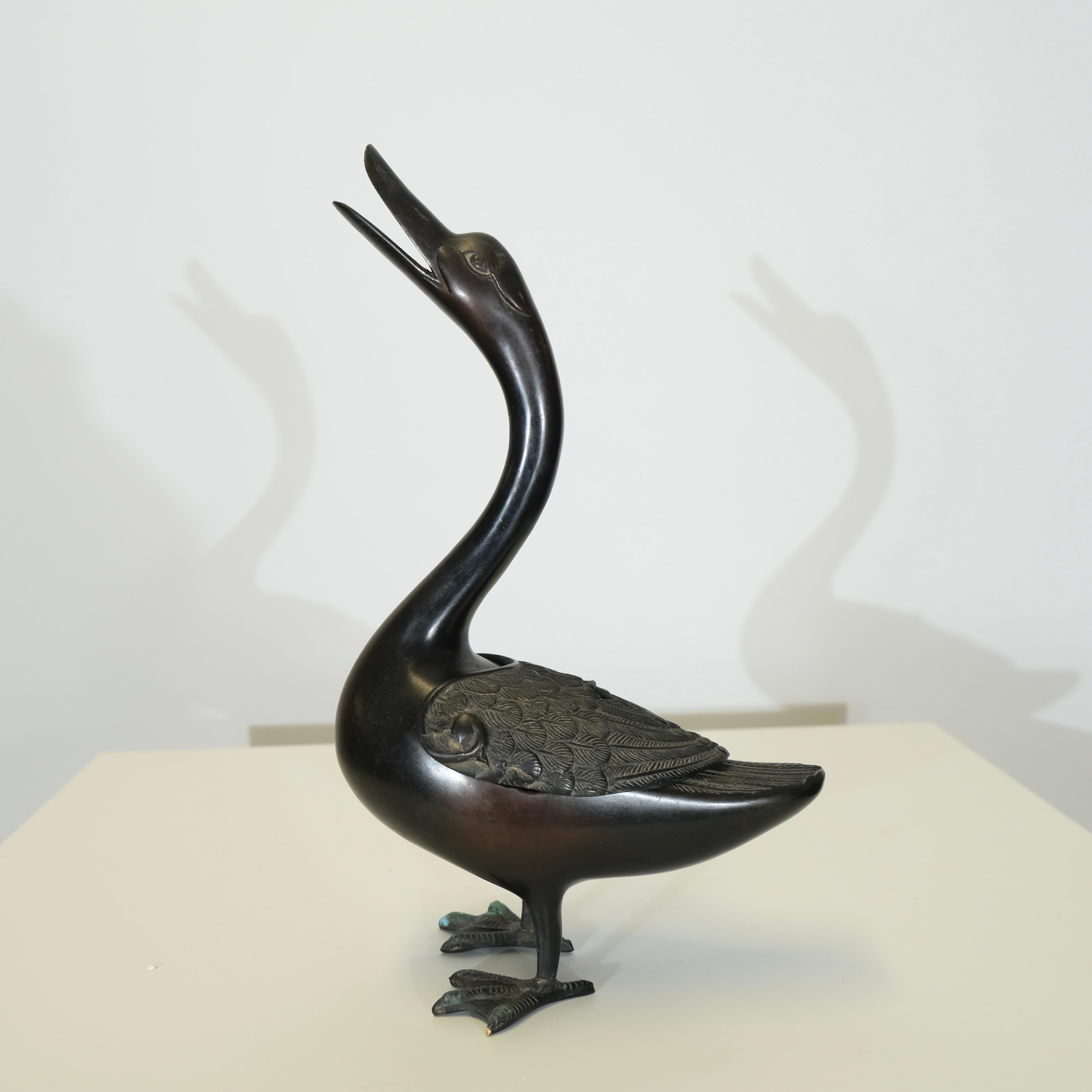 Questo incensiere giapponese in bronzo del XIX secolo è finemente fuso a forma di anatra con un collo elegantemente arcuato e un becco aperto, simbolo di longevità e pace nella cultura giapponese. Le ali piumate finemente dettagliate e il corpo