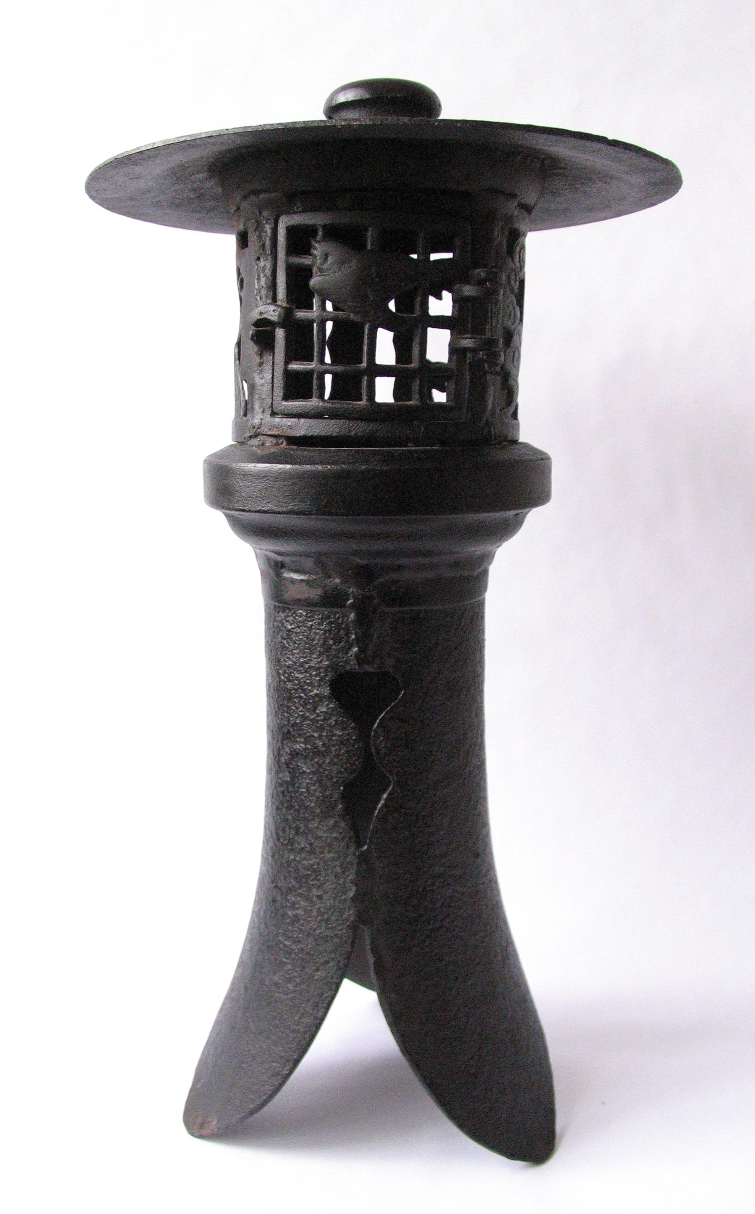 Midcentury Japanese cast iron pagoda lantern with lattice fret work hinged door.
Bird and bamboo iron cut outs surround pagoda. Beautiful sloped tripod base.