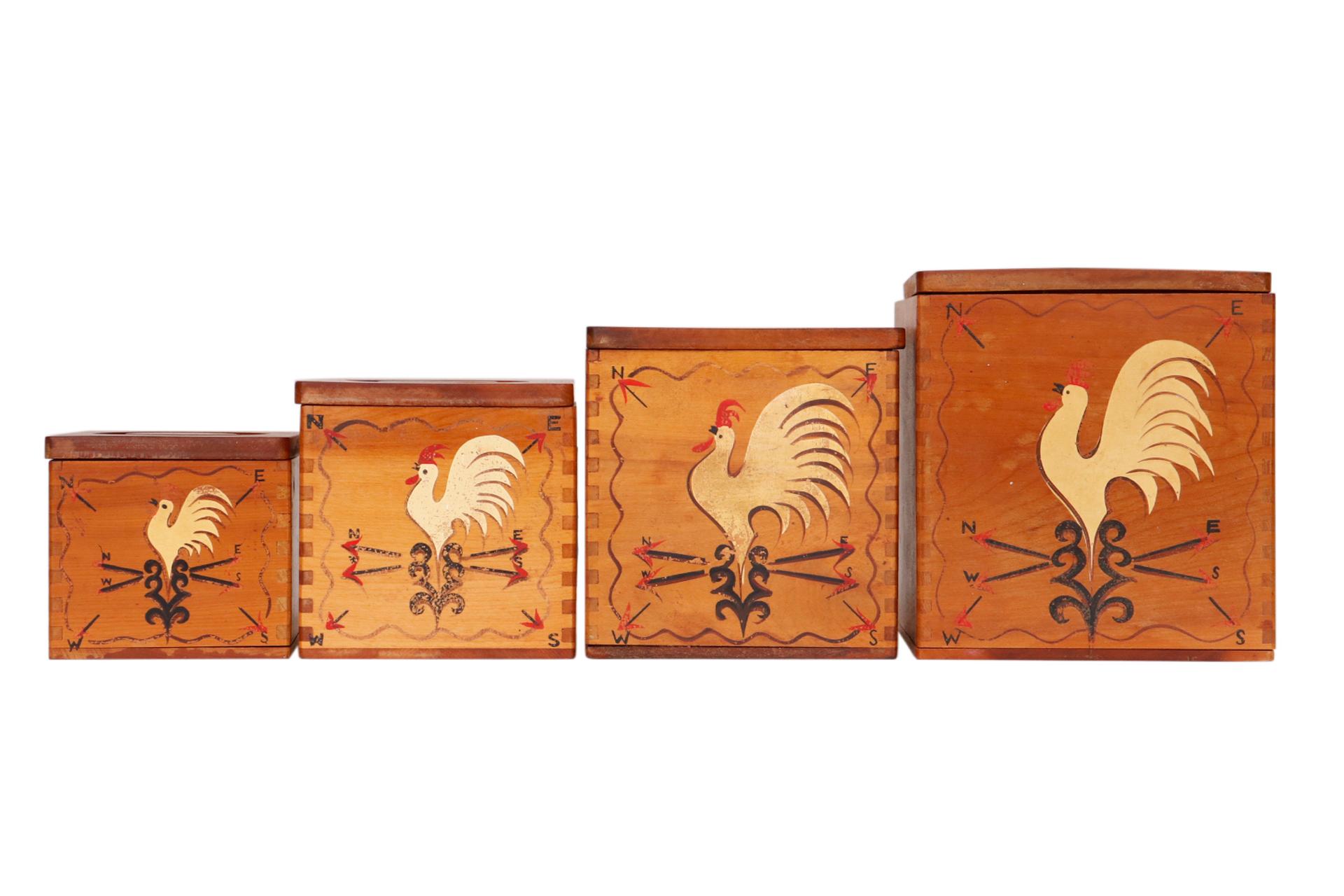 A set of four nesting kitchen canisters made of wood. Each is constructed with dovetailed corners and decorated in front with a chicken weathervane. Lids lift off with round recessed handles. Marked underneath “The Redbird Line, Hand Decorated
