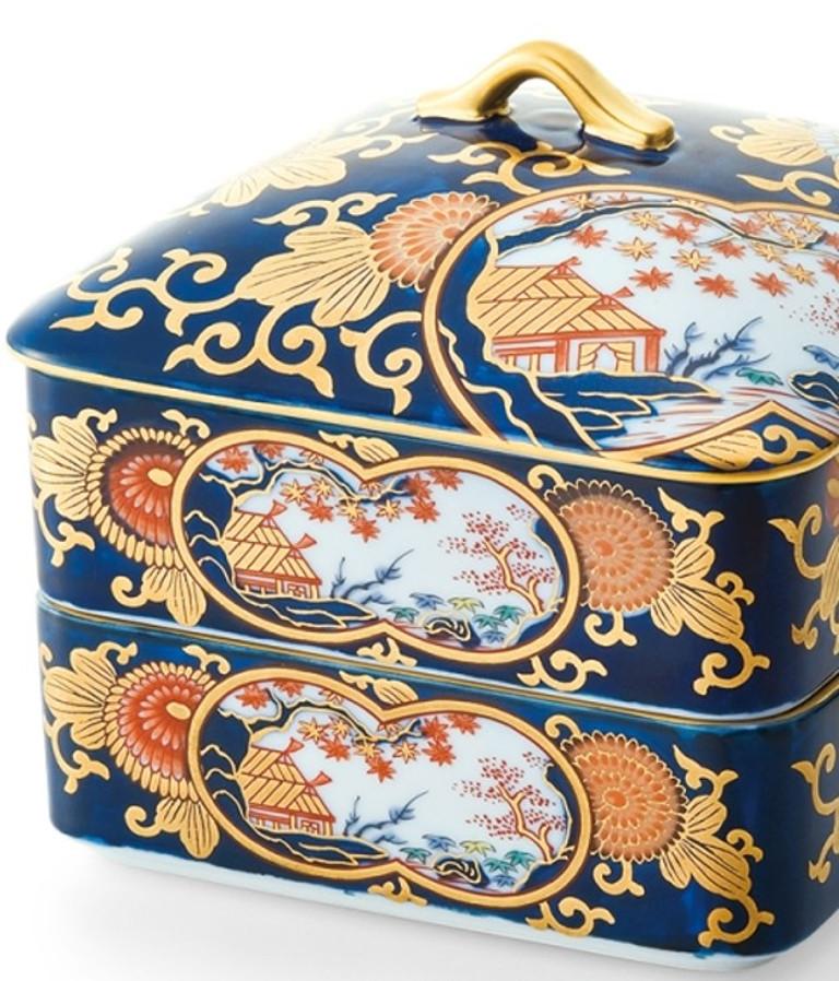 Contemporary Japanese Ko-Imari style two tiered lidded decorative porcelain box, intricately hand painted in cobalt blue, red and green and generous application of gold on a pure white porcelain, characteristic of Ko-Imari style.

The attractive