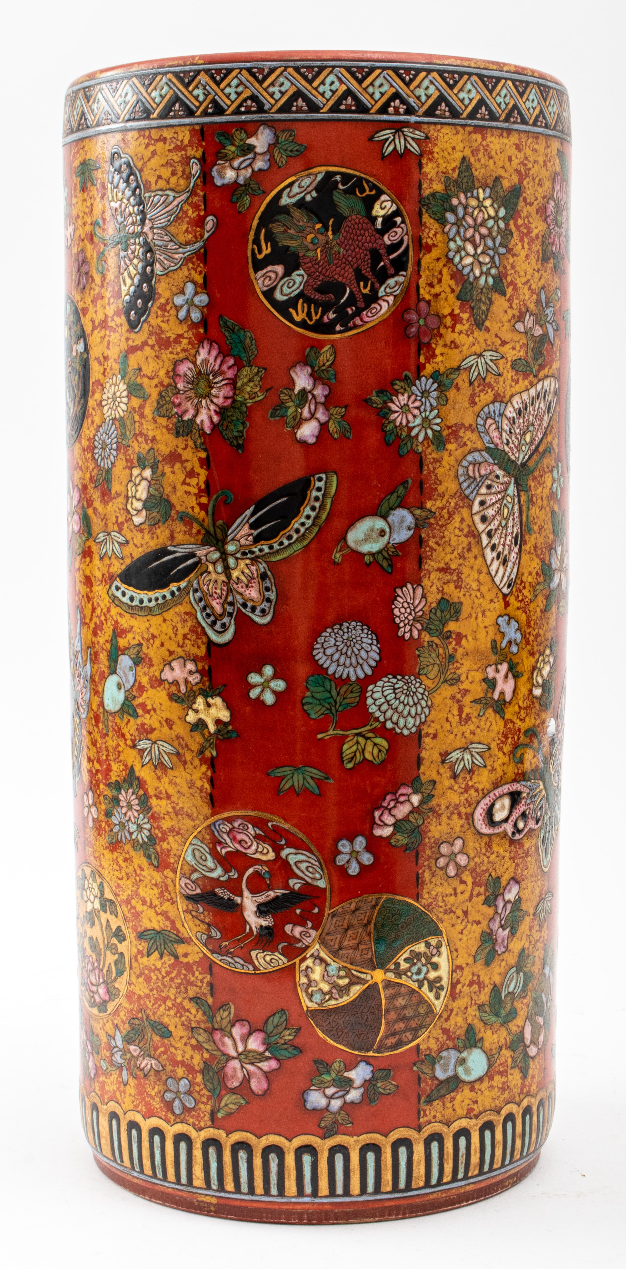 Japanese Kutani manner umbrella stand, depicting polychrome butterflies, flowers, fruits, and decorative roundels against a red ground with geometric banded decoration. 
Measures: 18.5