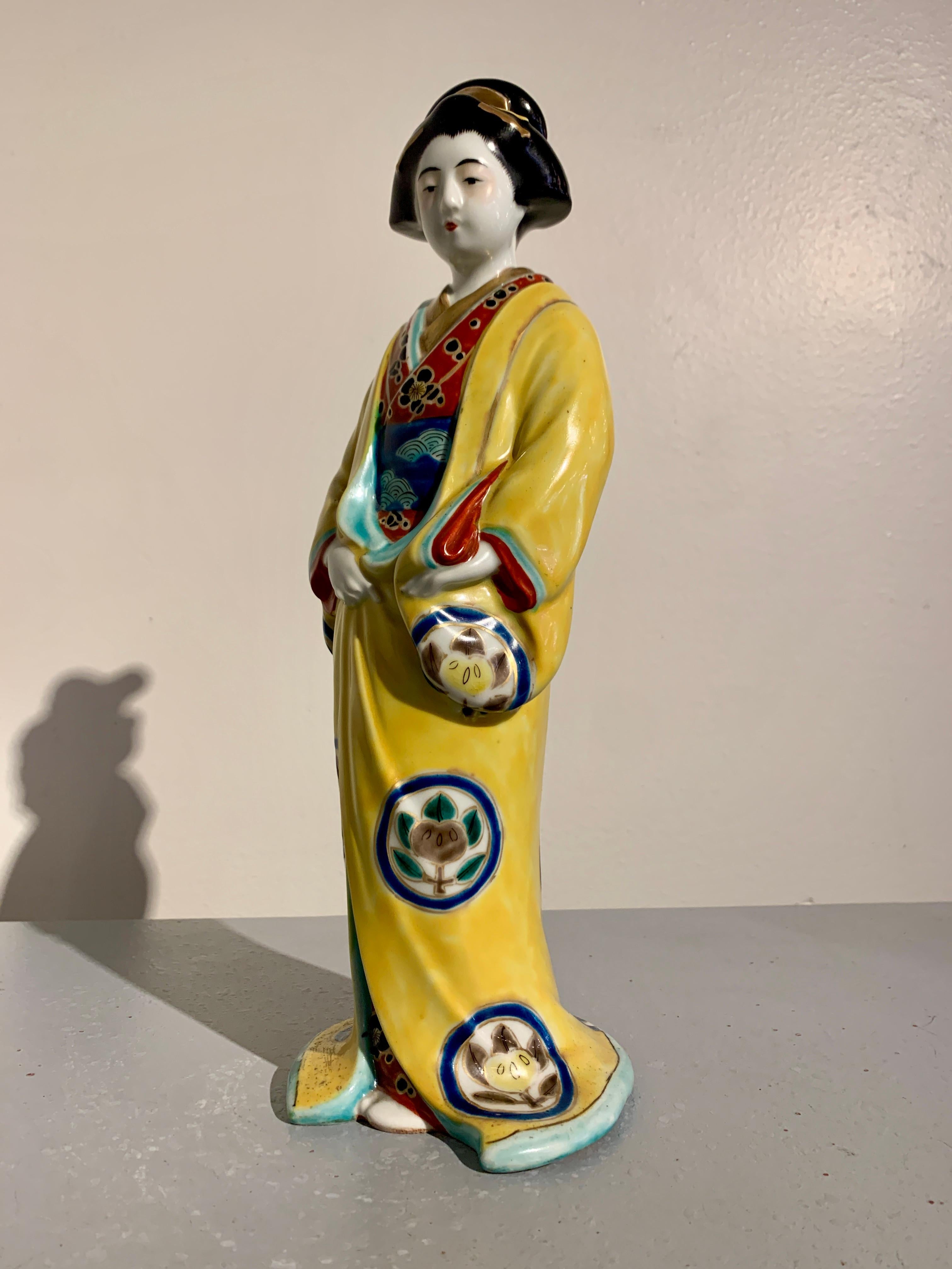 A delightful Japanese Kutani enameled porcelain figure of a bijin or geisha, early Showa Era, circa 1930's, Japan.

The elegant figure of a beautiful woman, called a bijin, or perhaps a giesha, is portrayed dressed in full kimono and an outer robe,