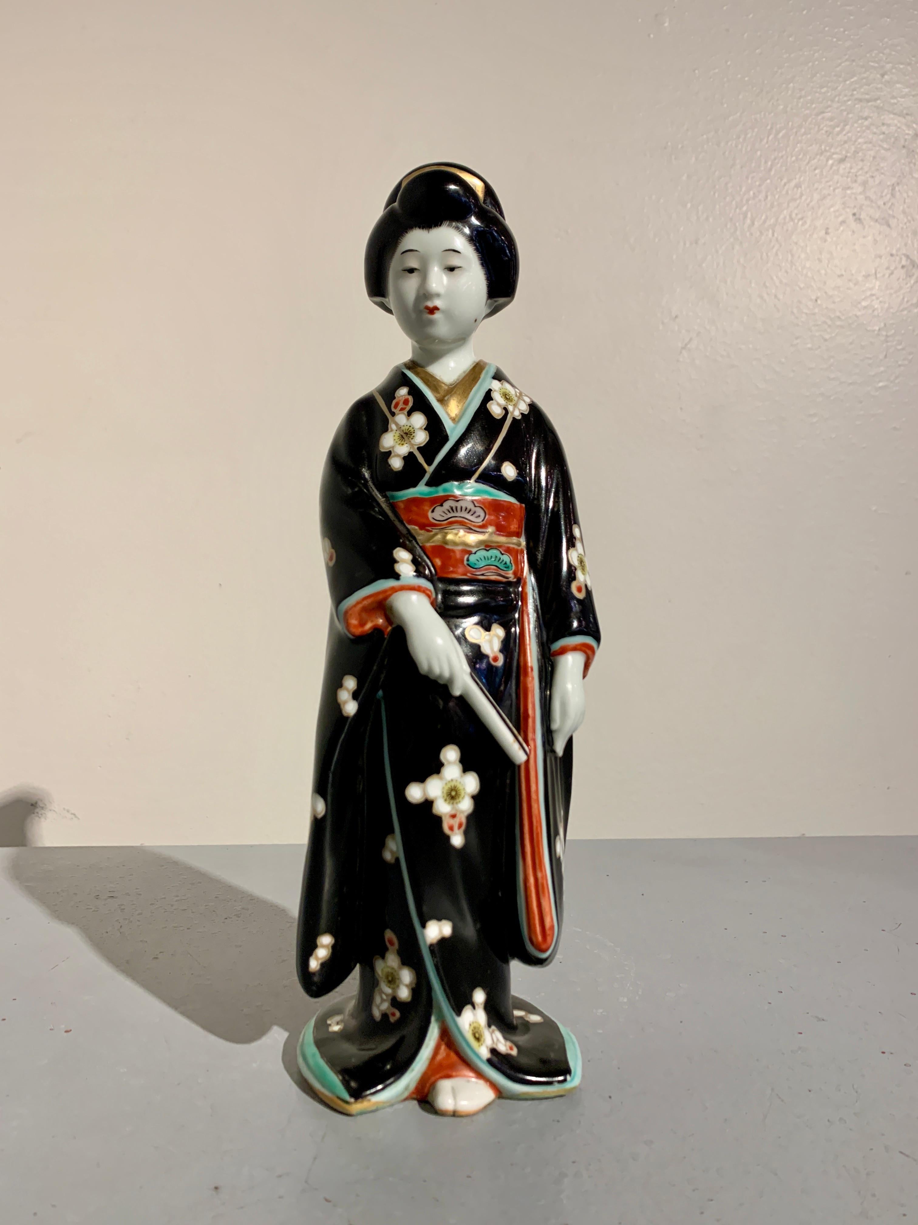 Eine charmante und reizvolle japanische Kutani emaillierte Porzellanfigur einer Bijin oder Geisha, frühe Showa-Ära, ca. 1930er Jahre, Japan.

Die elegante Figur einer schönen Frau, Bijin genannt, die in einen vollen Kimono gekleidet ist und einen
