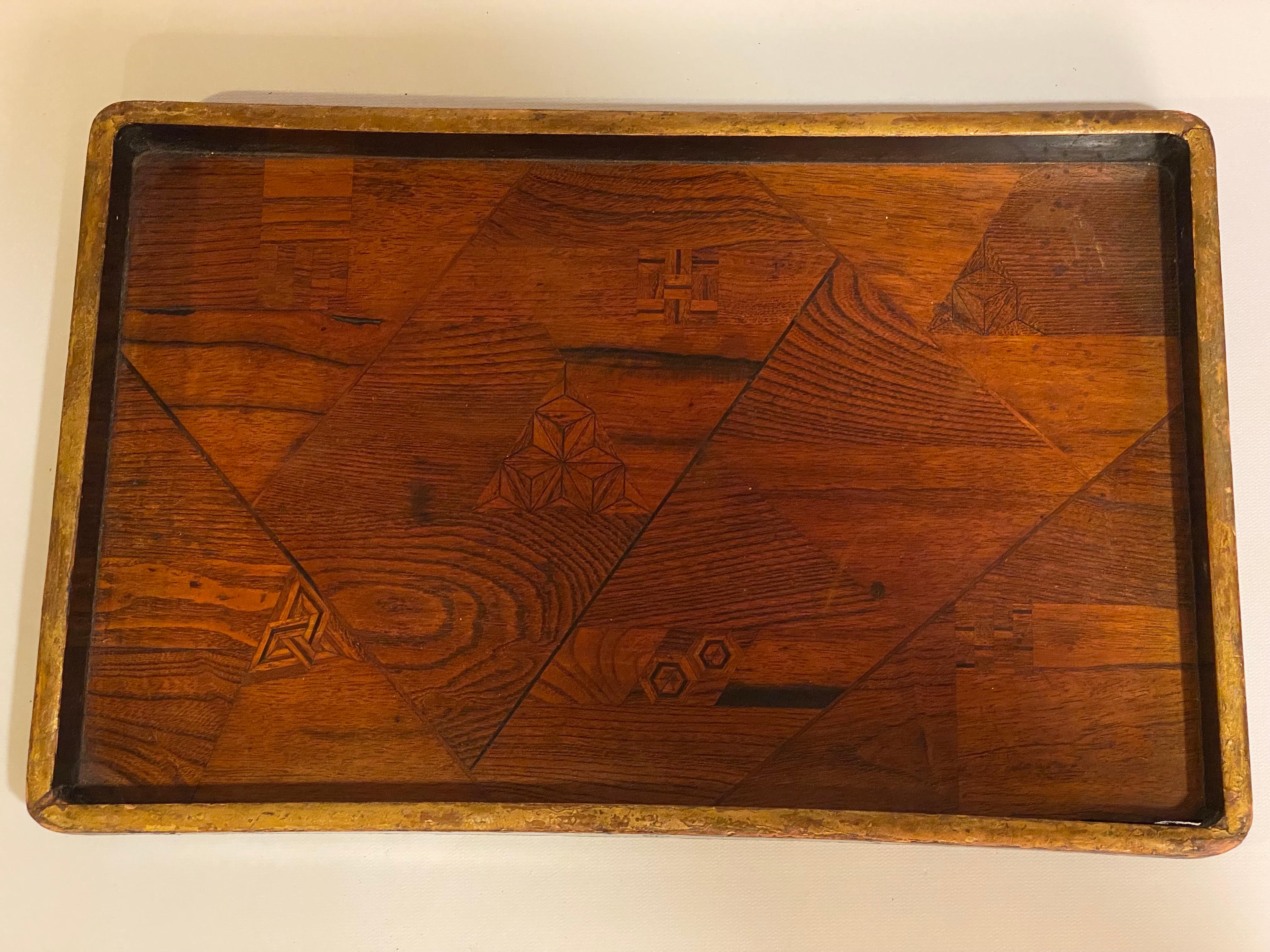 Japanese inlaid, lacquered and gilded tray. Possibly for the sacred tea ceremony. This tray has beautiful geometric inlays with a gilded edge and a black lacquer exterior. Circa 1880-1900. The inlays look to be oak, rosewood and some other exotic
