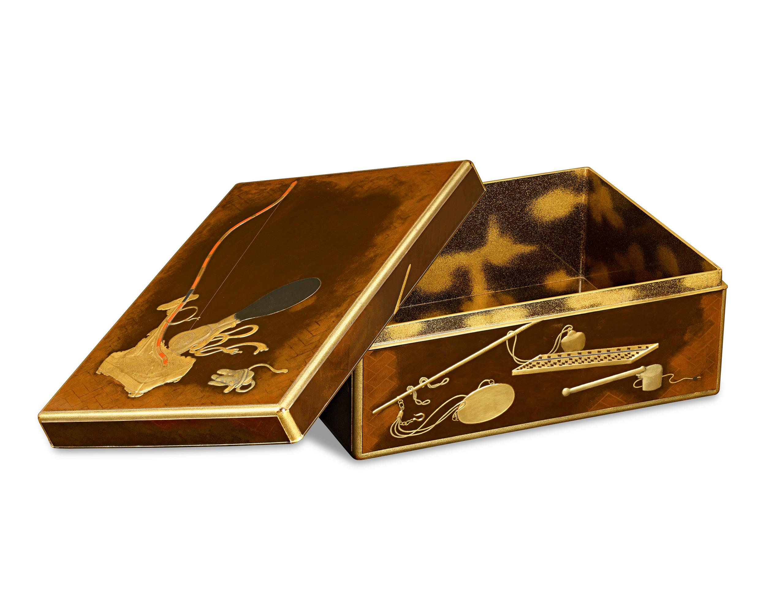 Cette exquise boîte à documents en laque de la période Meiji, connue sous le nom de ryoshibako, témoigne de l'art méticuleux du maki-e, une technique de décoration en laque en relief. Ornée d'or et de couleurs vives, elle comporte des emblèmes