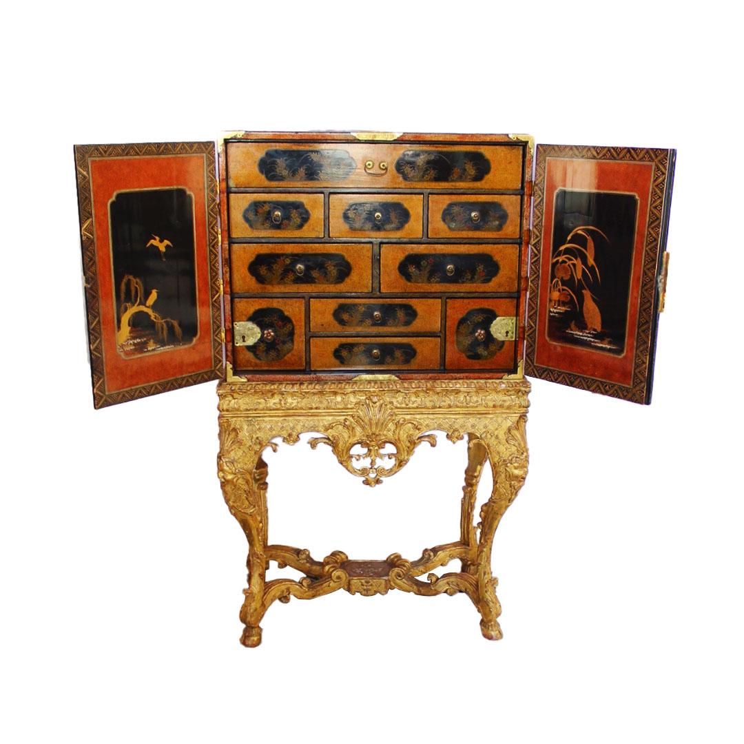 Japanese lacquer cabinet on Regence Giltwood stand. The stand - Circa 1725 and the lacquer cabinet - late 17th/early 18th Century. Decorated overall with figures in a landscape and doors opening to drawers. The cabriole legs are headed by masks on