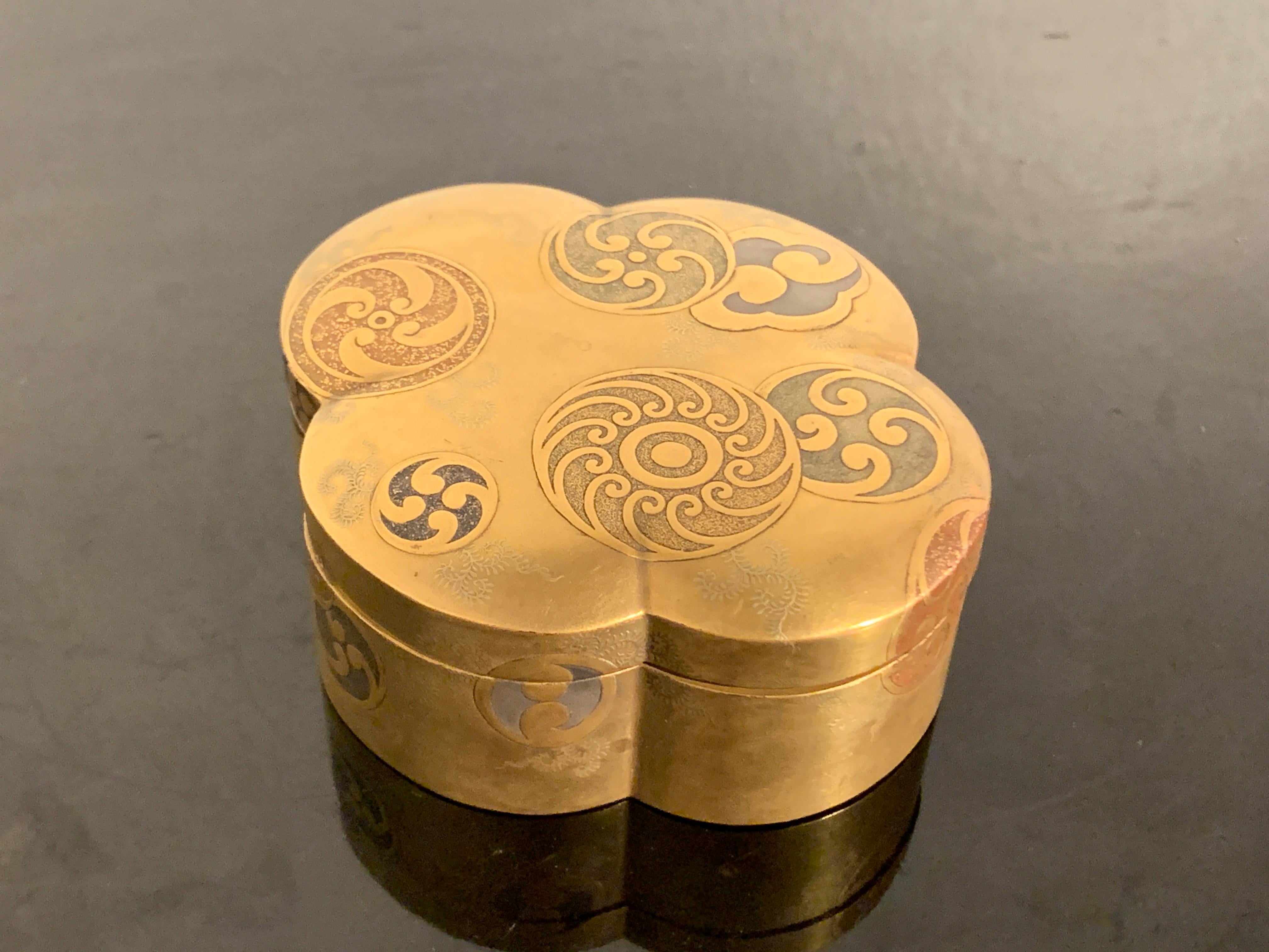 A lovely and graphic Japanese small incense box, kogo, with various tomoe mon, Taisho period (1912 - 1926), Japan.

The small box of quatrefoil form, with rounded edges and a slightly domed lid. The small box decorated with a gold lacquer ground,