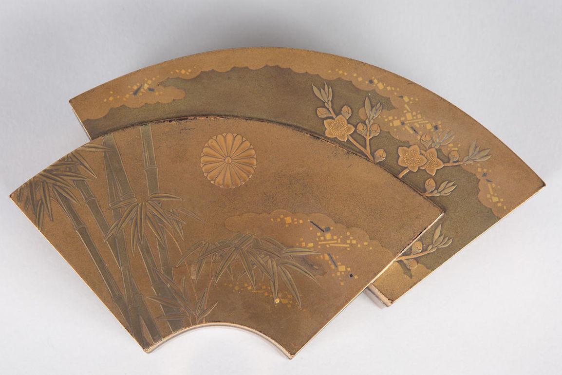 Räucherstäbchenbehälter aus der späten Edo-Periode (1614 - 1868) in gestapeltem, doppeltem Fächerdesign. Die Fächer haben ein Bambus- und Pflaumenmuster mit einem Chrysanthemenwappen. Rand und Sitz aus silbernem Metall, Innenausstattung aus