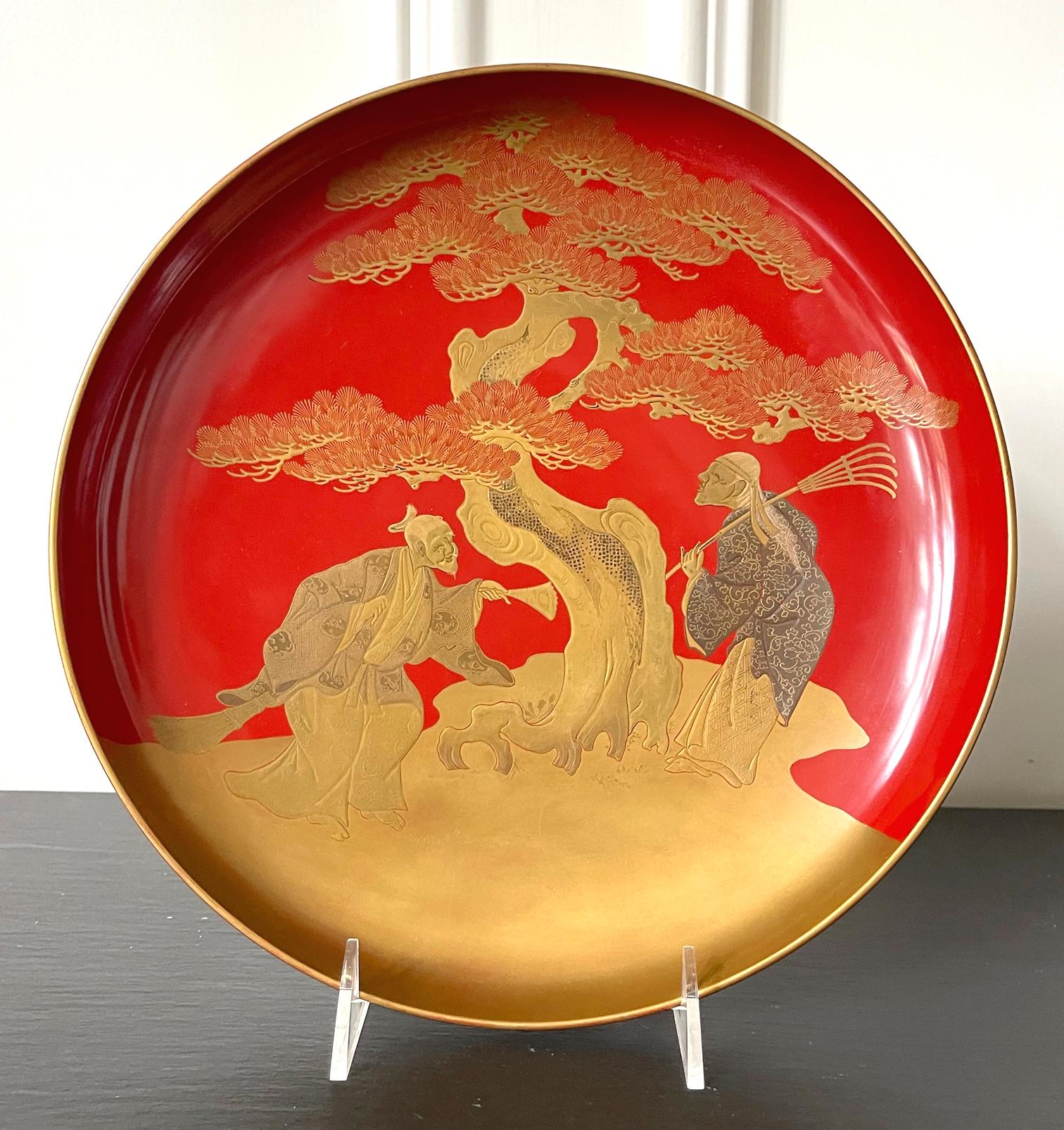 A large circular plate with a short stem base in Vermillion lacquer color from Late Meiji Period circa end of 19th century to early 20th century. The surface was decorated with a very fine maki-e picture that depicts Takasago story. The legend is