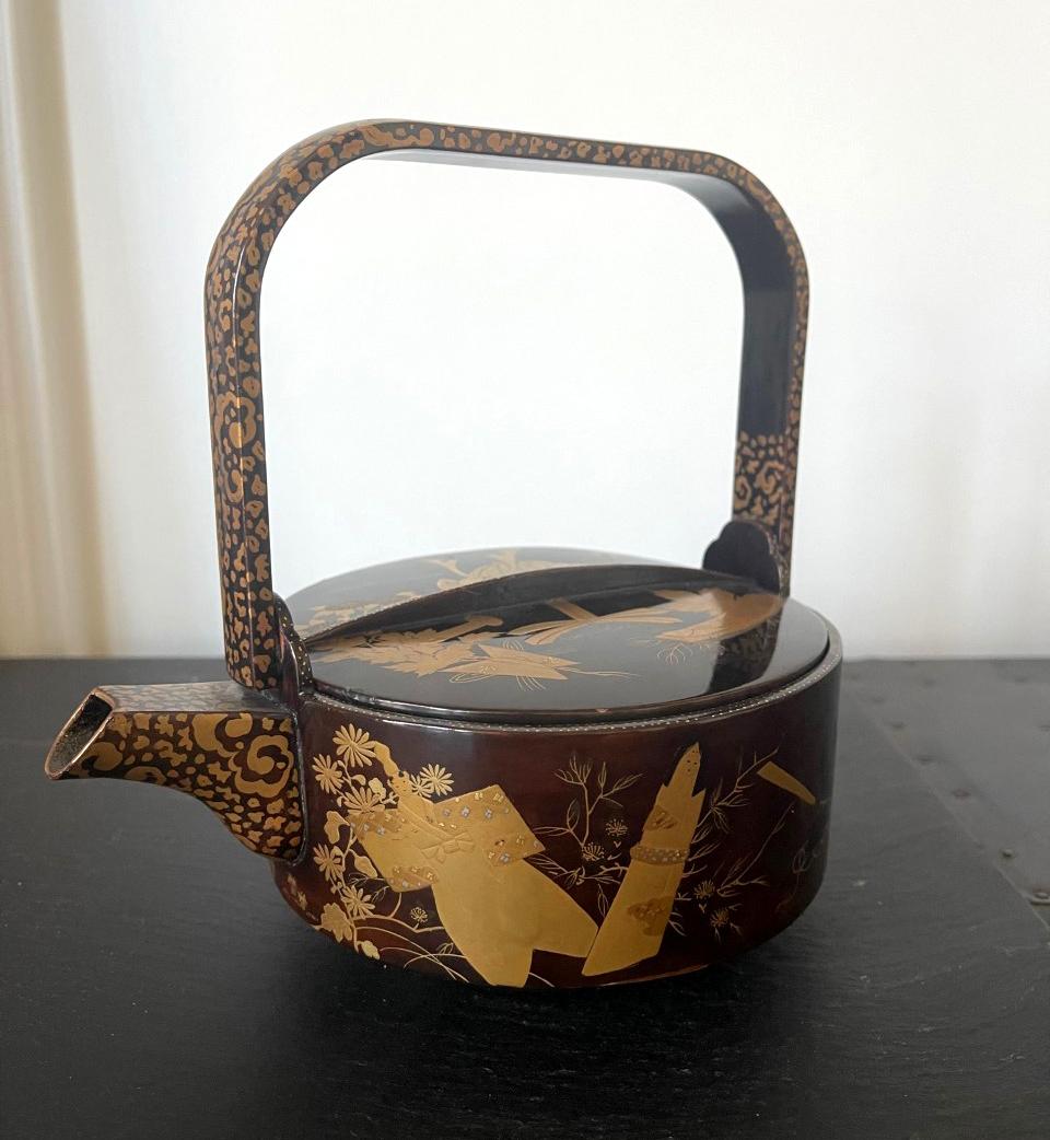A Japanese lacquered wood sake ewer with maki-e design, circa late 19th century, Meiji period. The nicely decorated lacquerware is of a Classic sake ewer form with a round body, a small short sprout, a highly raised handle and three small supporting