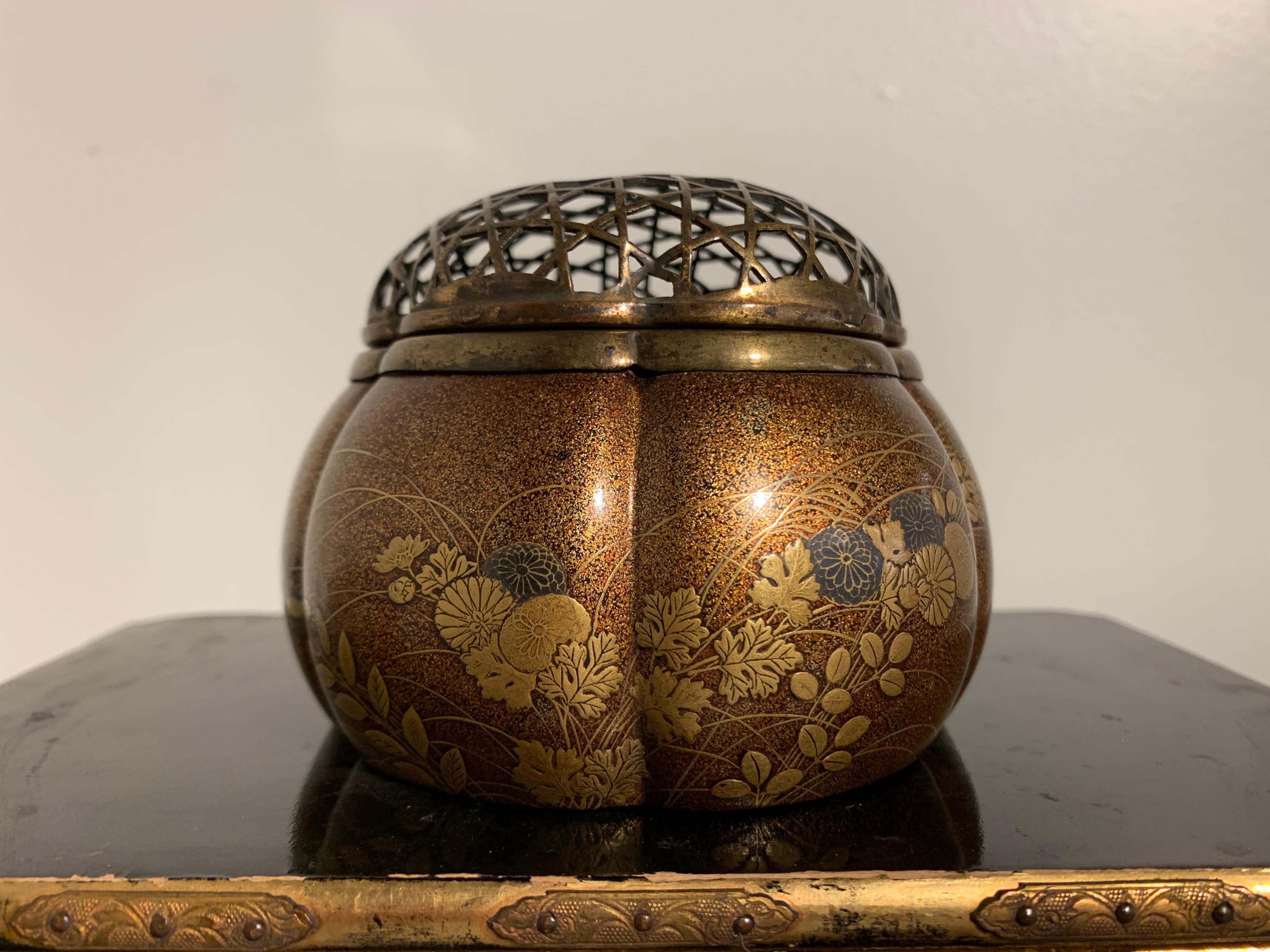 A very fine Japanese lacquer incense burner, akoda koro, of melon form with a design of autumnal grasses and chrysanthemum blossoms, with a gilt metal openwork cover, Edo Period, 17th-18th century, Japan.

The koro (censer) crafted of lacquer over