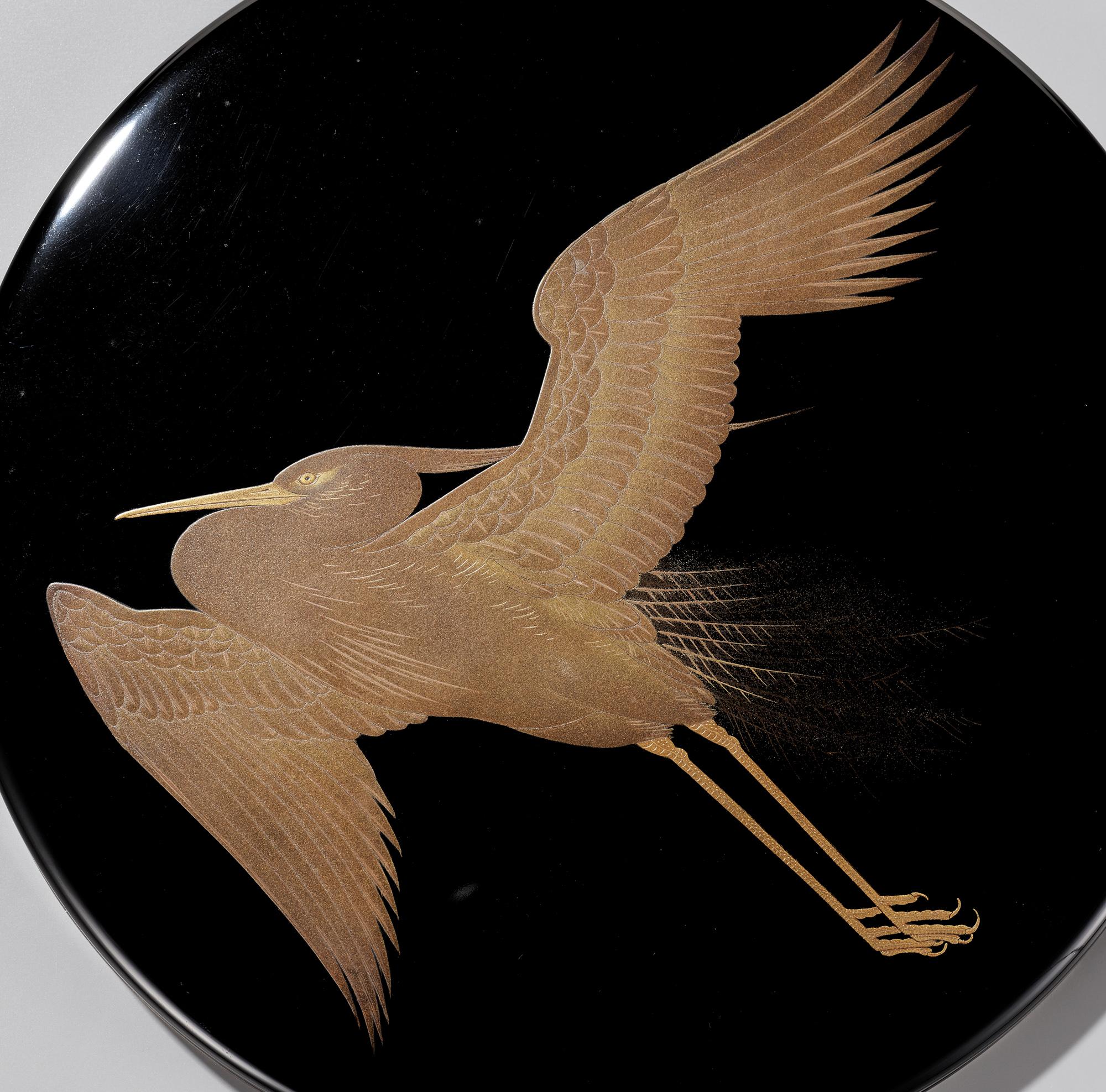 An exquisite lacquer suzuri’bako (writing box) of circular form depicting a flying heron (shirasagi) with its wings spread out.

The flush-fitting cover finished with a rim of silver, and its motif executed in takamaki-e (high-relief lacquer design)